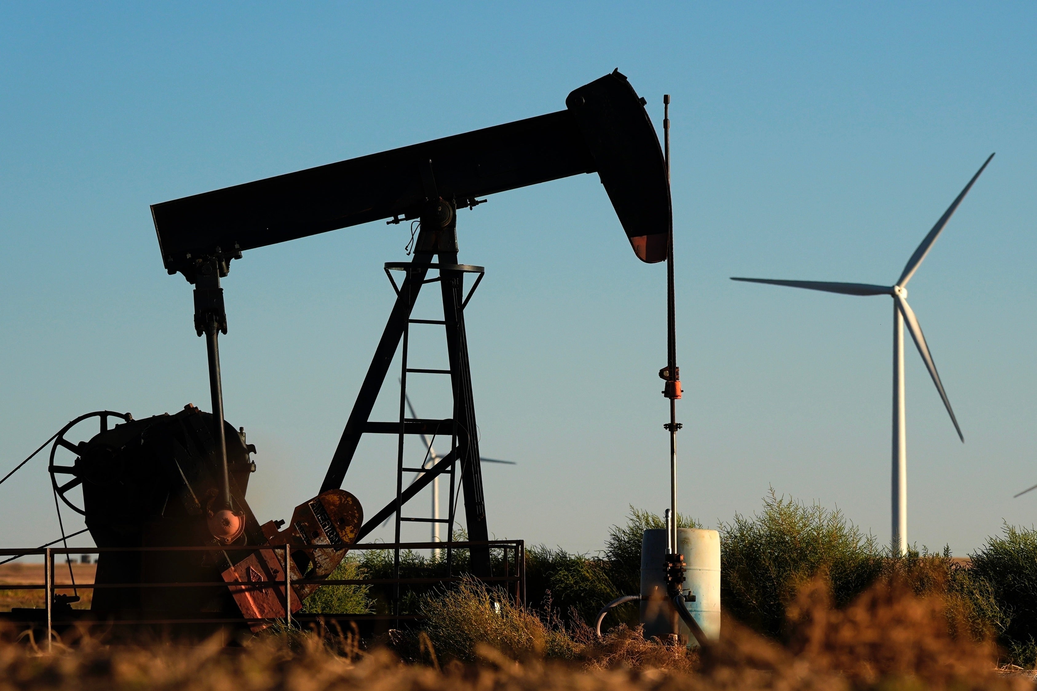 Oil pumpjacks operate in the foreground as the Buckeye Wind Energy wind farm rises in the distance last year near Hays, Kansas