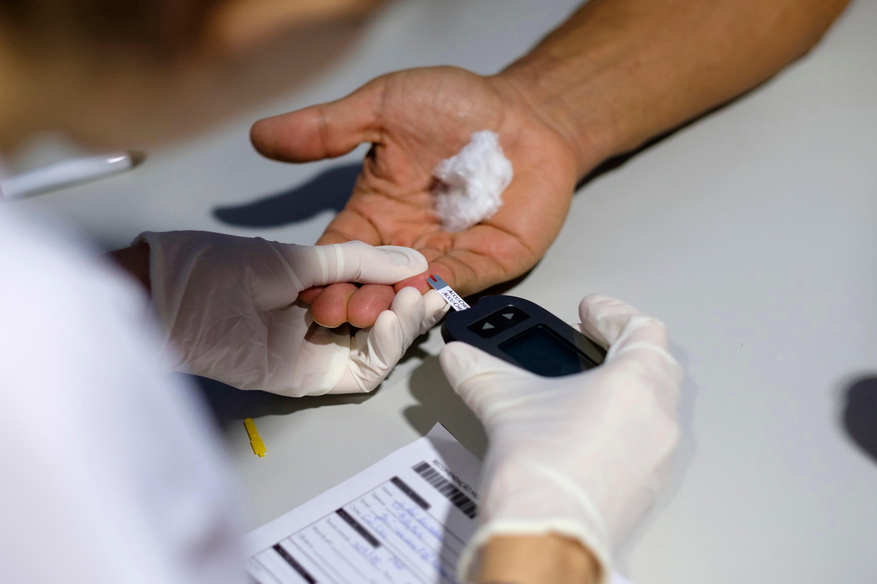 Medical worker using a blood glucose meter to test a patient for diabetes (Alamy/PA)