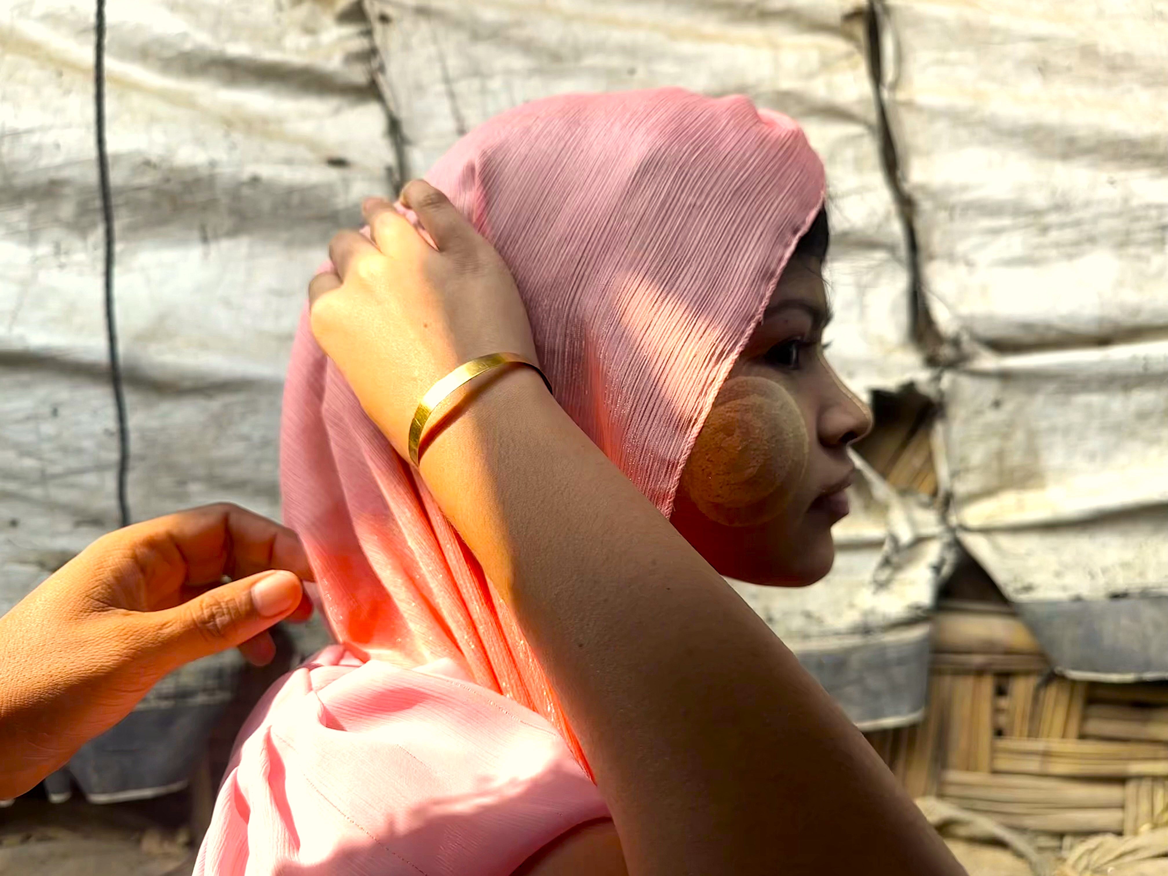 A Rohingya refugee girl wearing a thanaka, a yellow paste made from ground tree bark, on her face in a camp in January 2025 in Cox's Bazar, Bangladesh