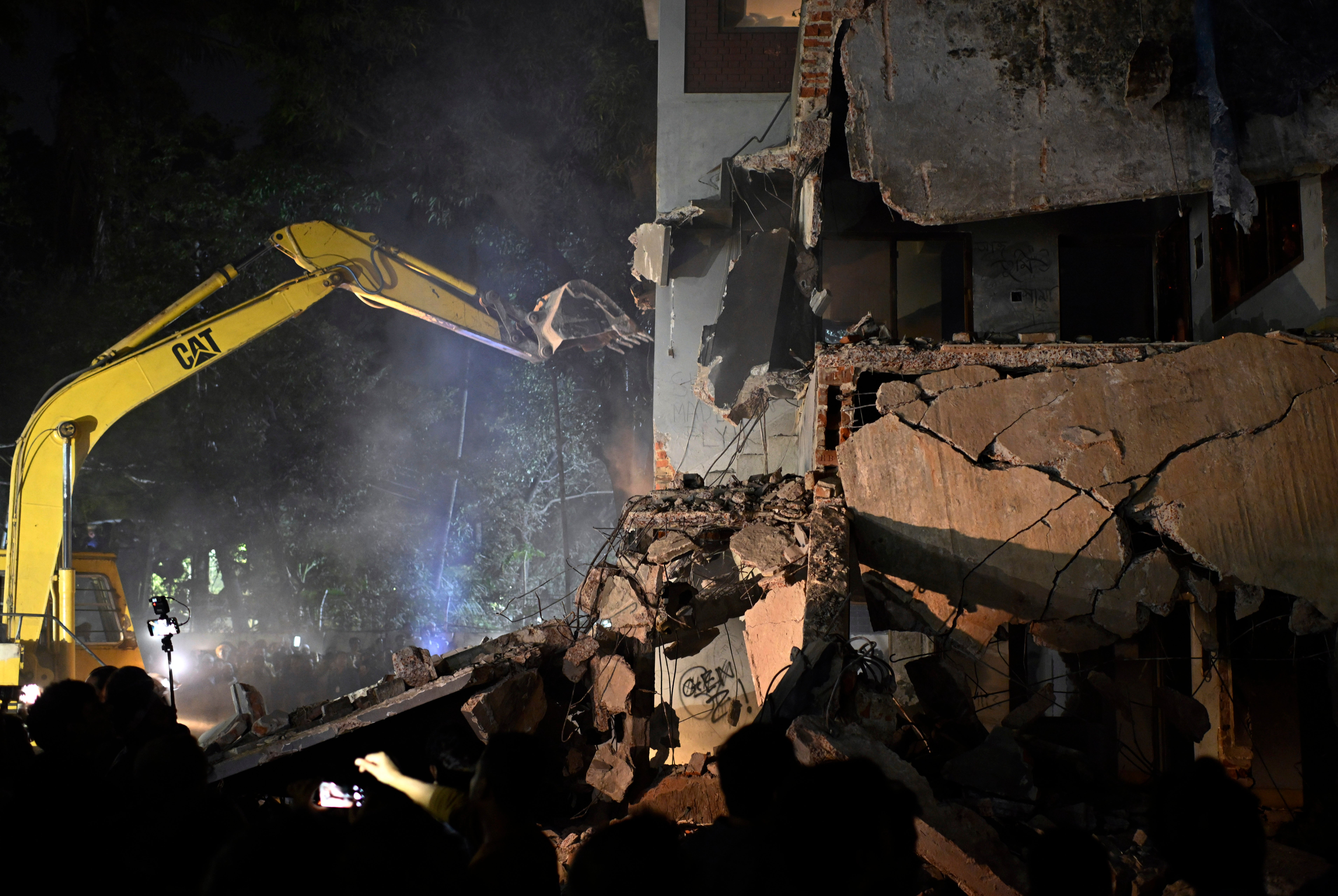 <p>People watch as protesters use heavy machinery to demolish the residence of late Bangladesh leader Sheikh Mujibur Rahman</p>