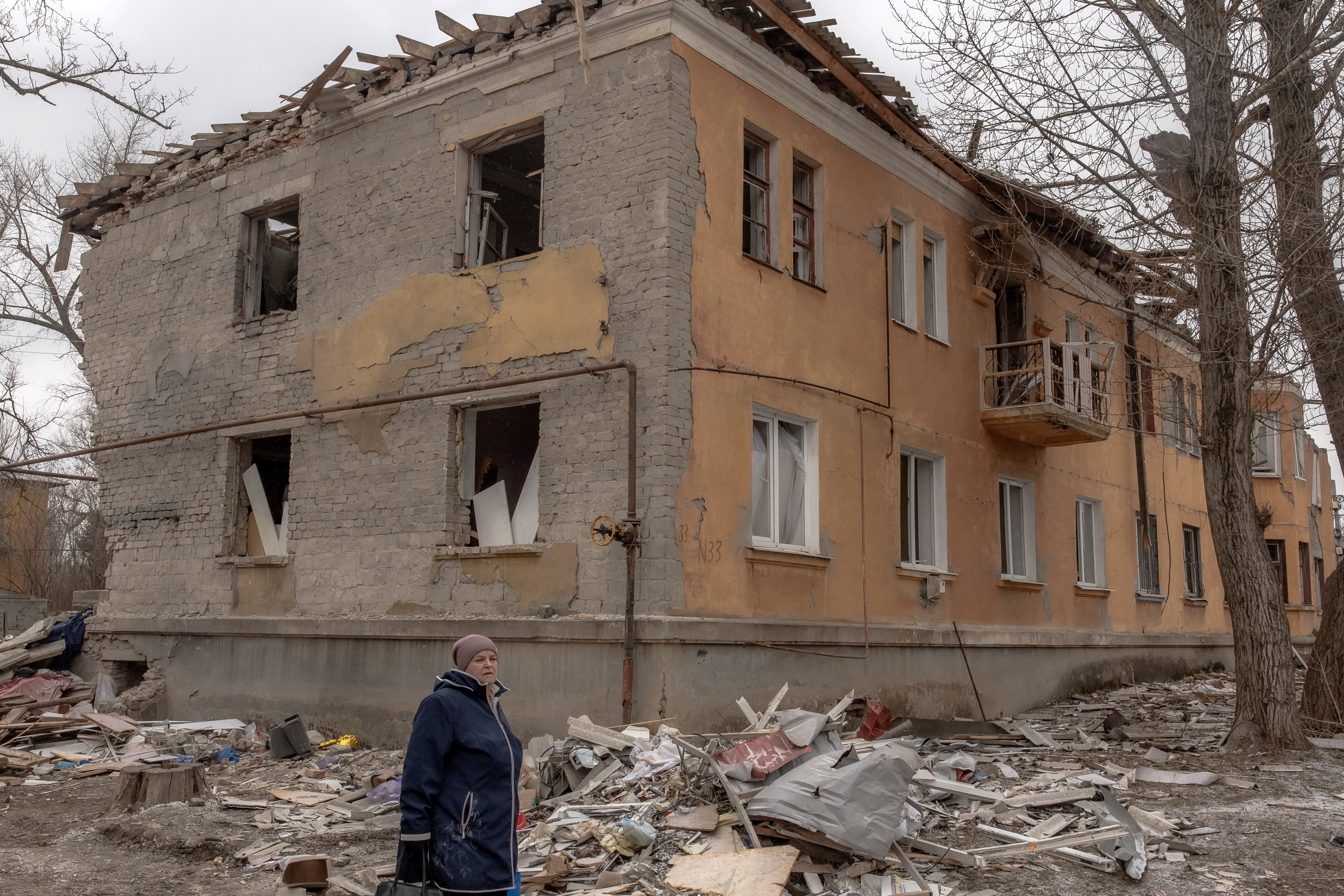 A woman walks past a residential building destroyed by shelling in Kostyantynivka, in the eastern Donetsk region