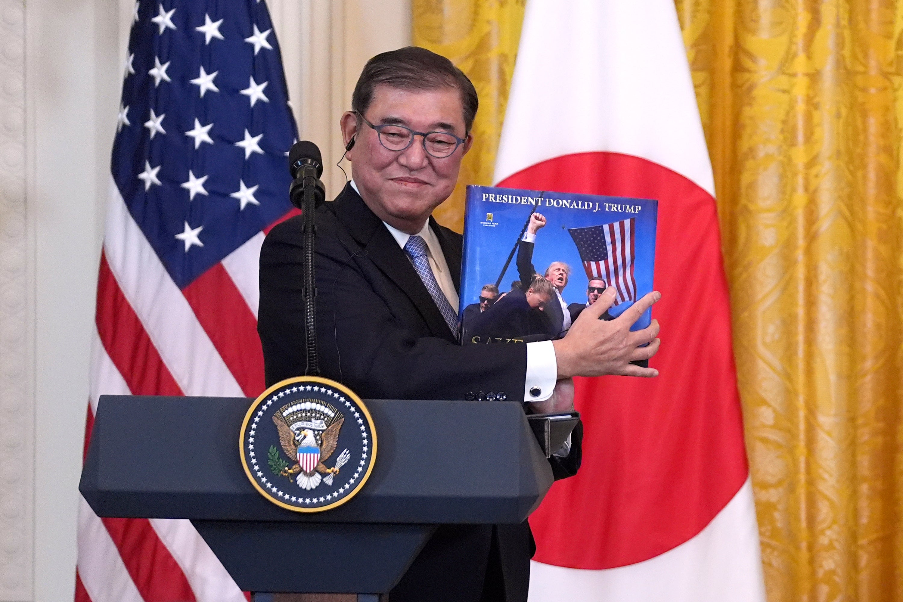 Ishiba holds a book presented by President Donald Trump