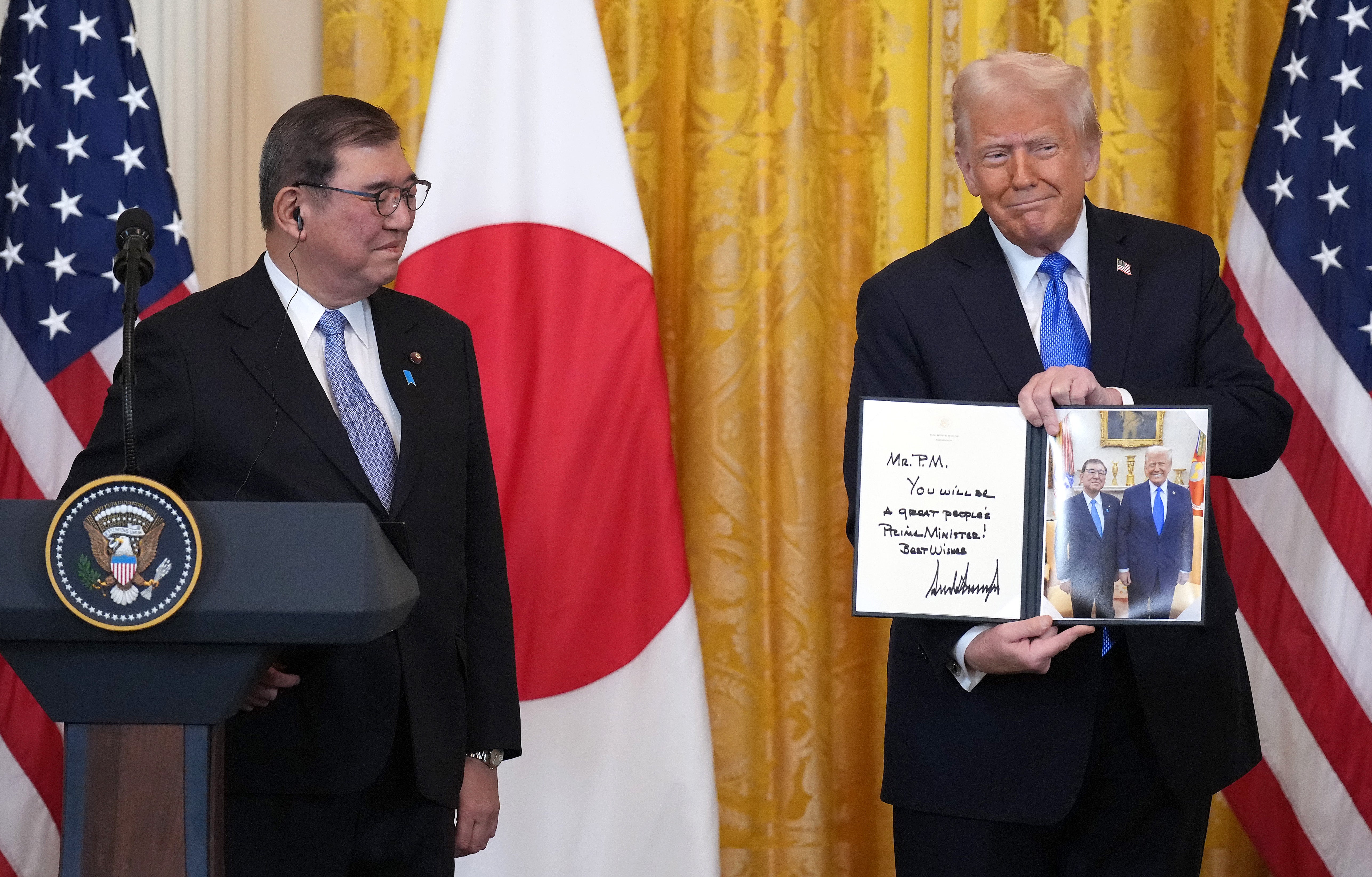 President Donald Trump gifts Japanese Prime Minister Shigeru Ishiba a signed photo during a joint press conference in the East Room at the White House