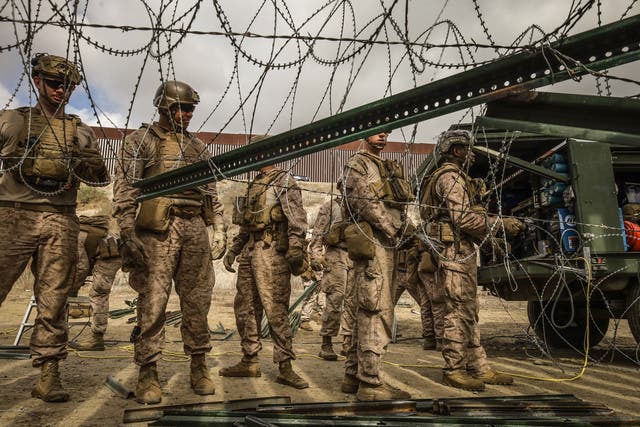 <p>US army members reinforce a wall with barbed wire on the border with the city of Tijuana, Mexico, in February</p>