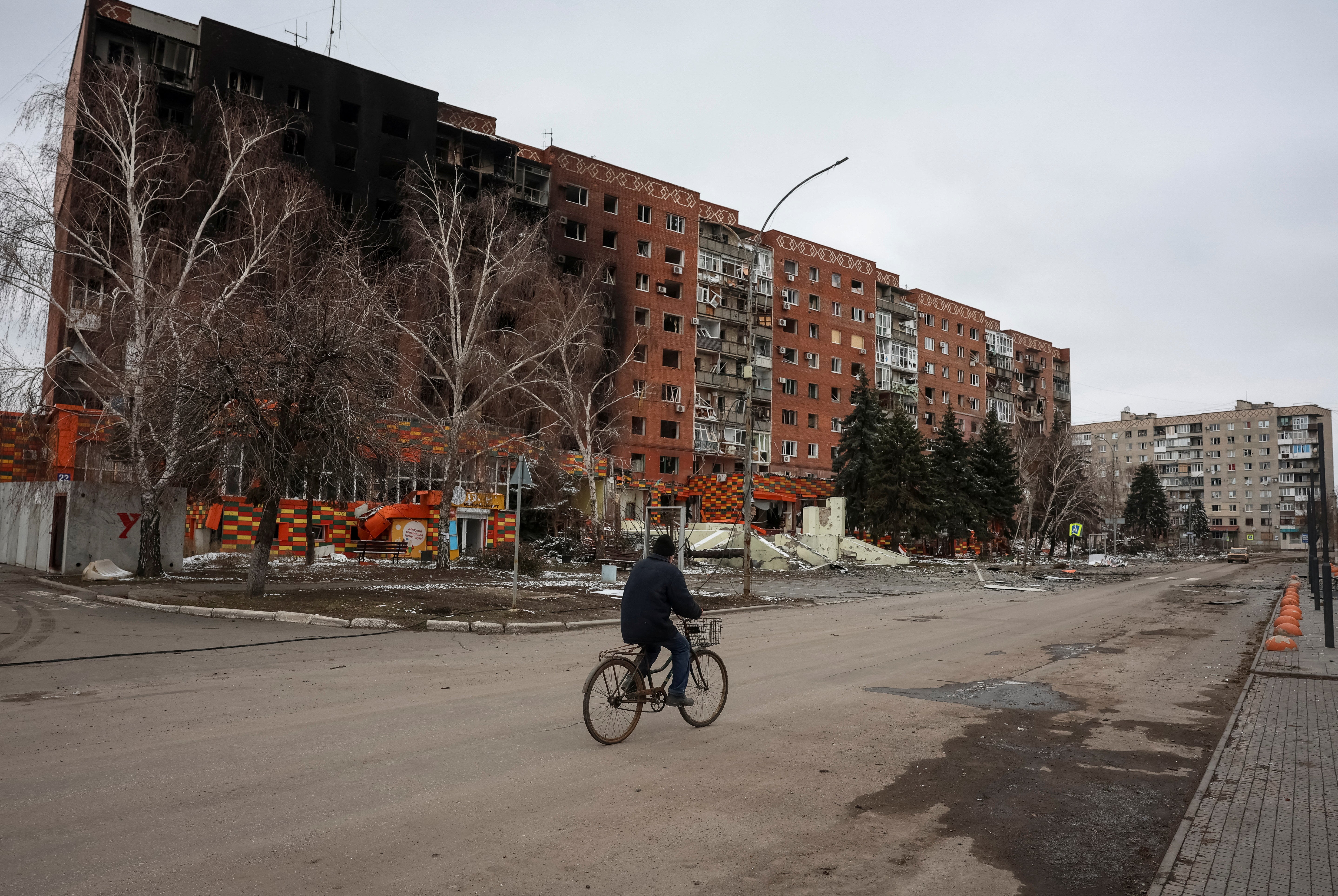 A resident rides a bicycle near a building damaged by Russian military strikes in Pokrovsk