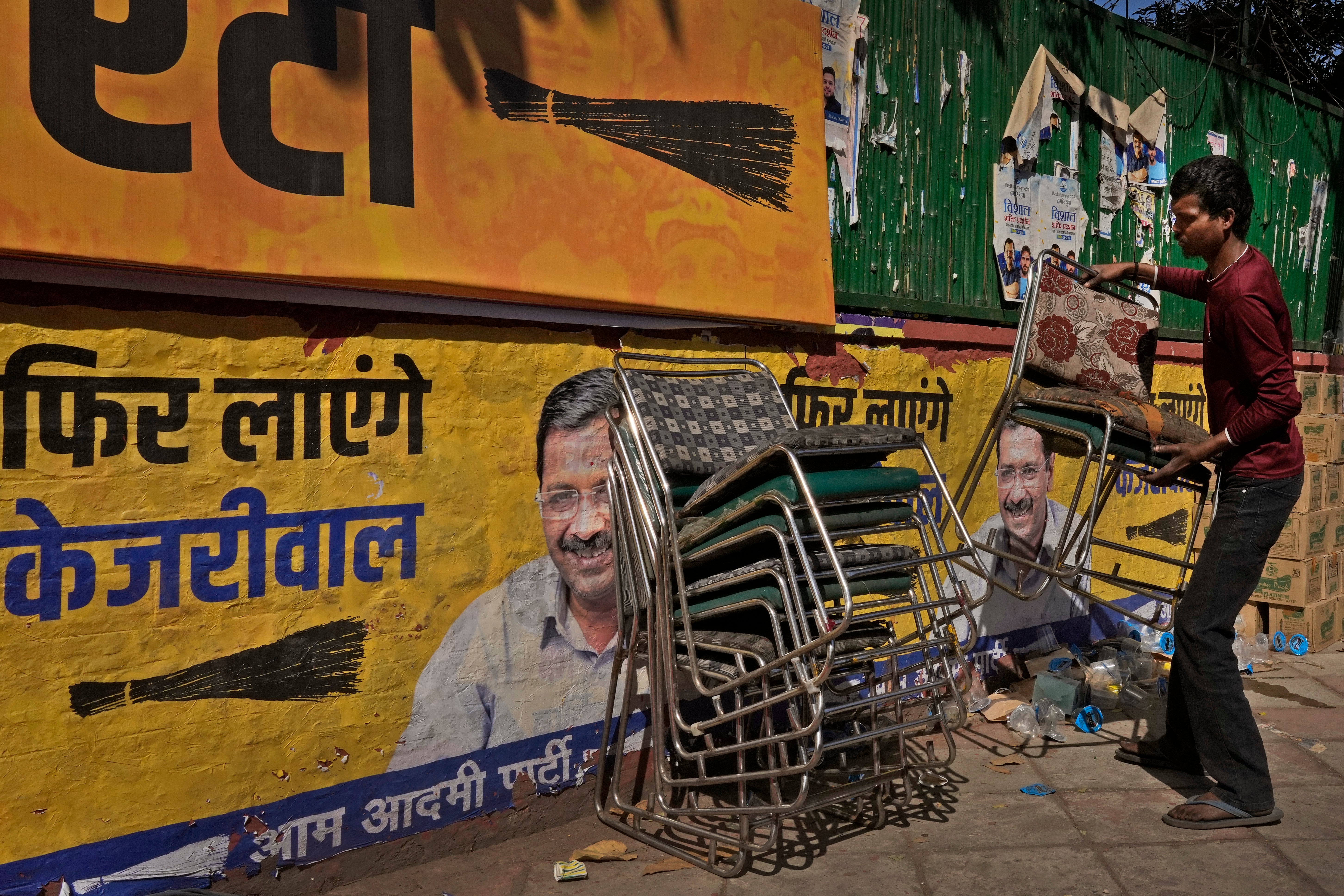 A worker removes and stacks chairs from Aam Aadmi Party (AAP) office as the party trails in Delhi state election in New Delhi, India