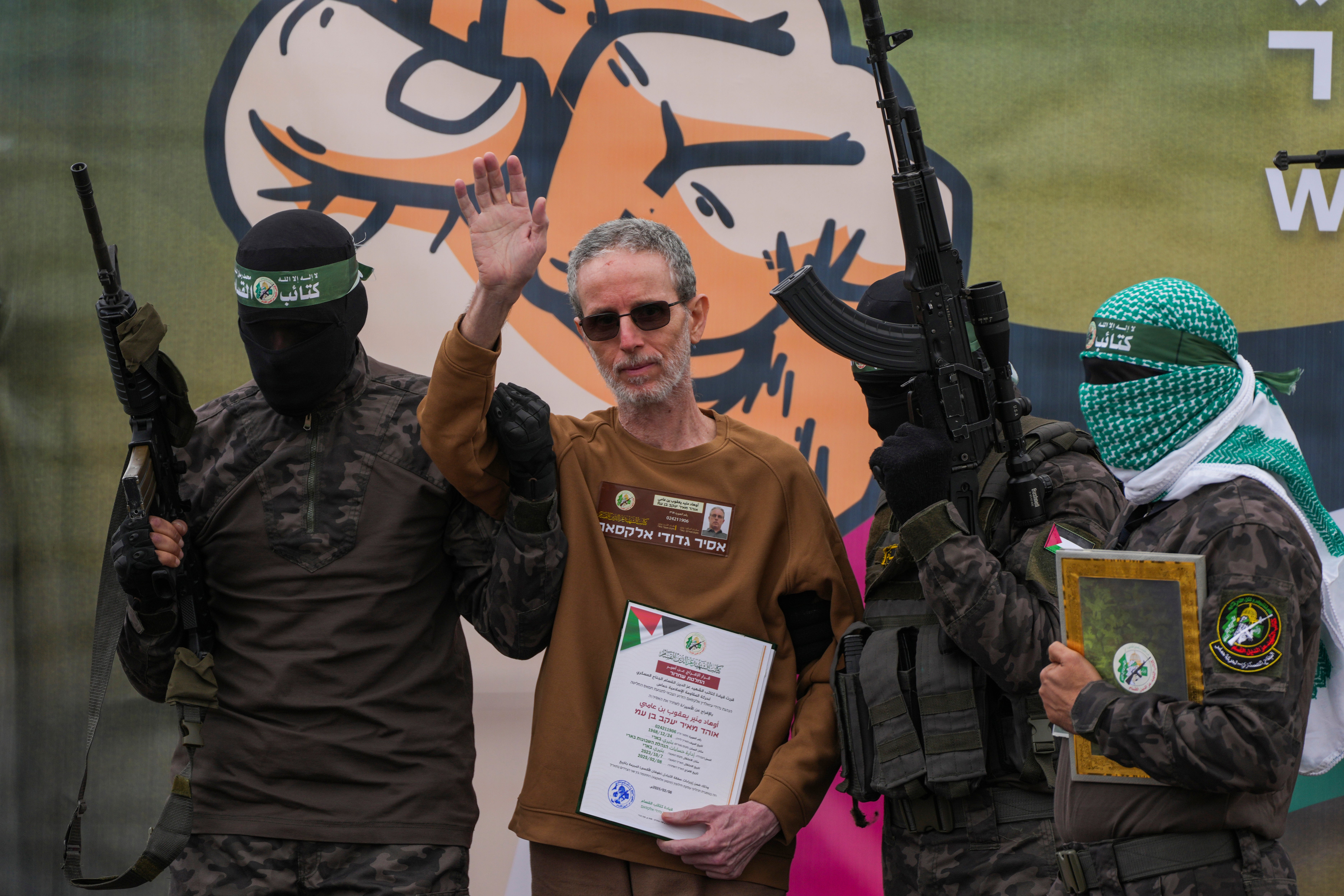 Israeli captive, Ohad Ben Ami, who has been held hostage by Hamas in Gaza since October 7, 2023, waves as he is escorted by Hamas fighters before being handed over to the Red Cross