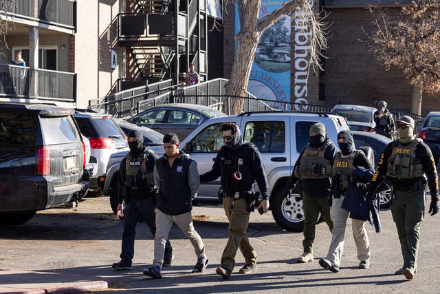 <p>Federal agents detain a man after conducting a raid at the Cedar Run apartment complex in Denver on February 5</p>