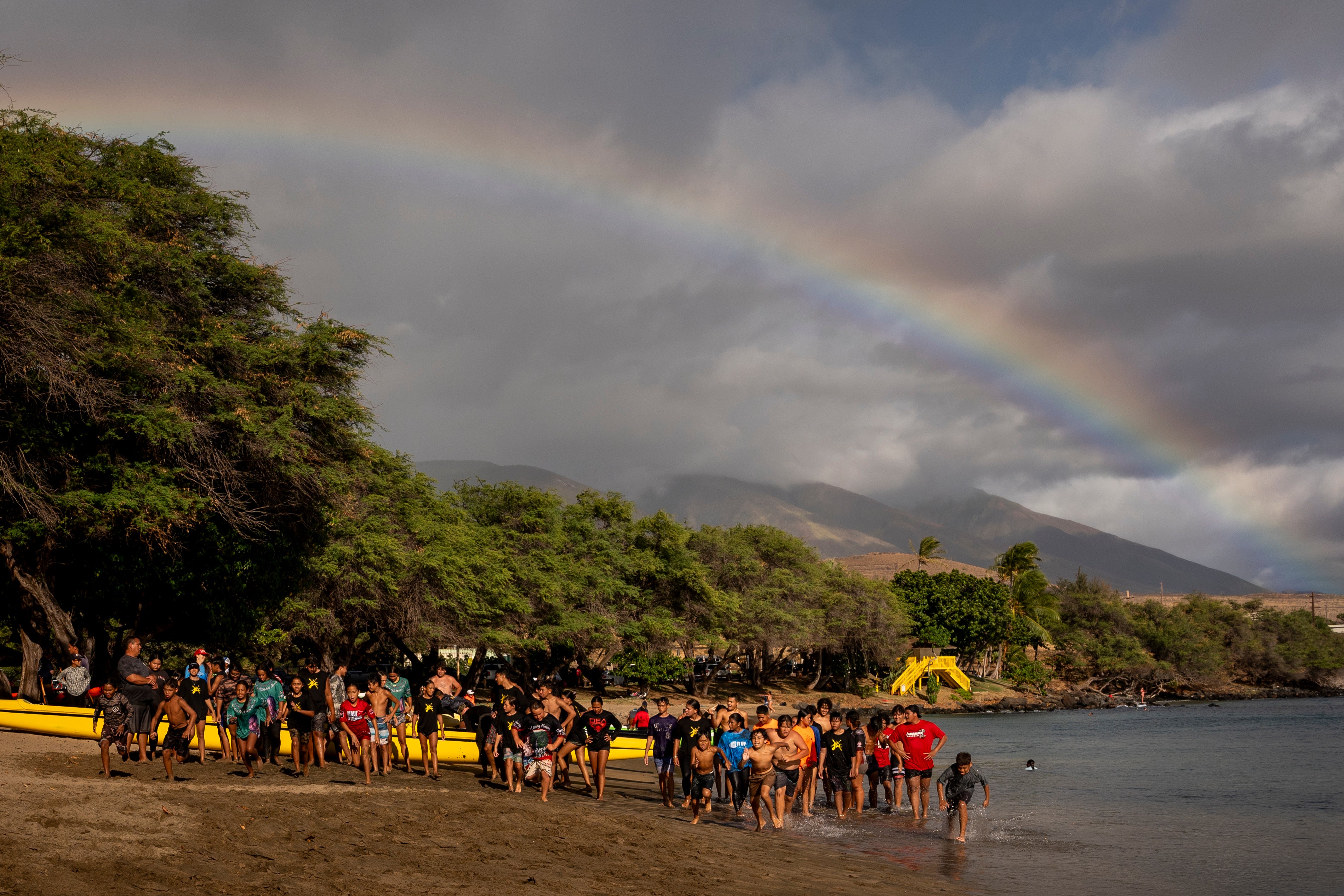 Los miembros del Napili Canoe Club corren en la playa cuando se forma un arco iris cercano el lunes 8 de julio de 2024 en Hanakao '