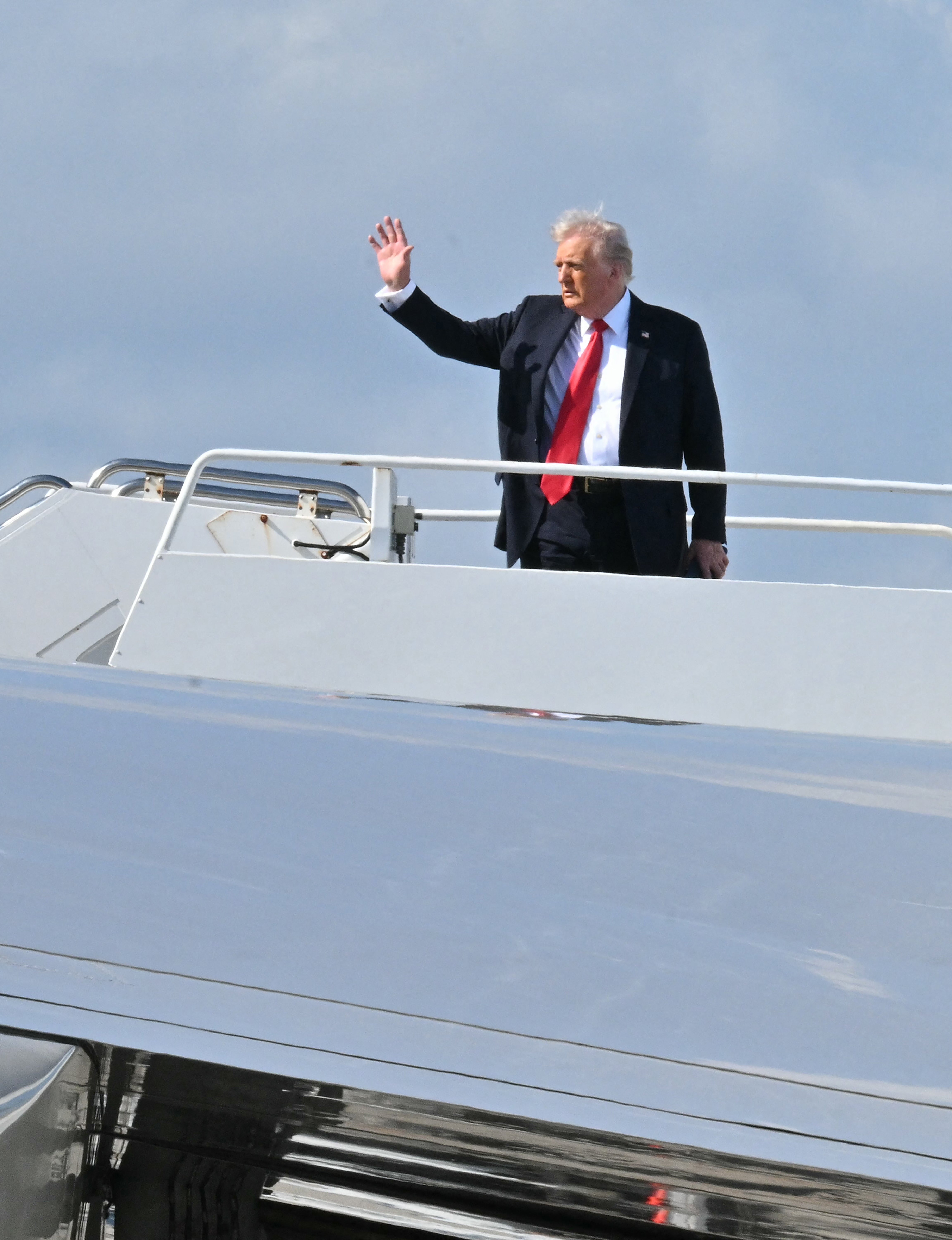 US President Donald Trump waves as he boards Air Force One at Palm Beach International Airport in West Palm Beach, Florida