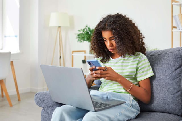 <p>A teenager on her phone (Alamy/PA)</p>