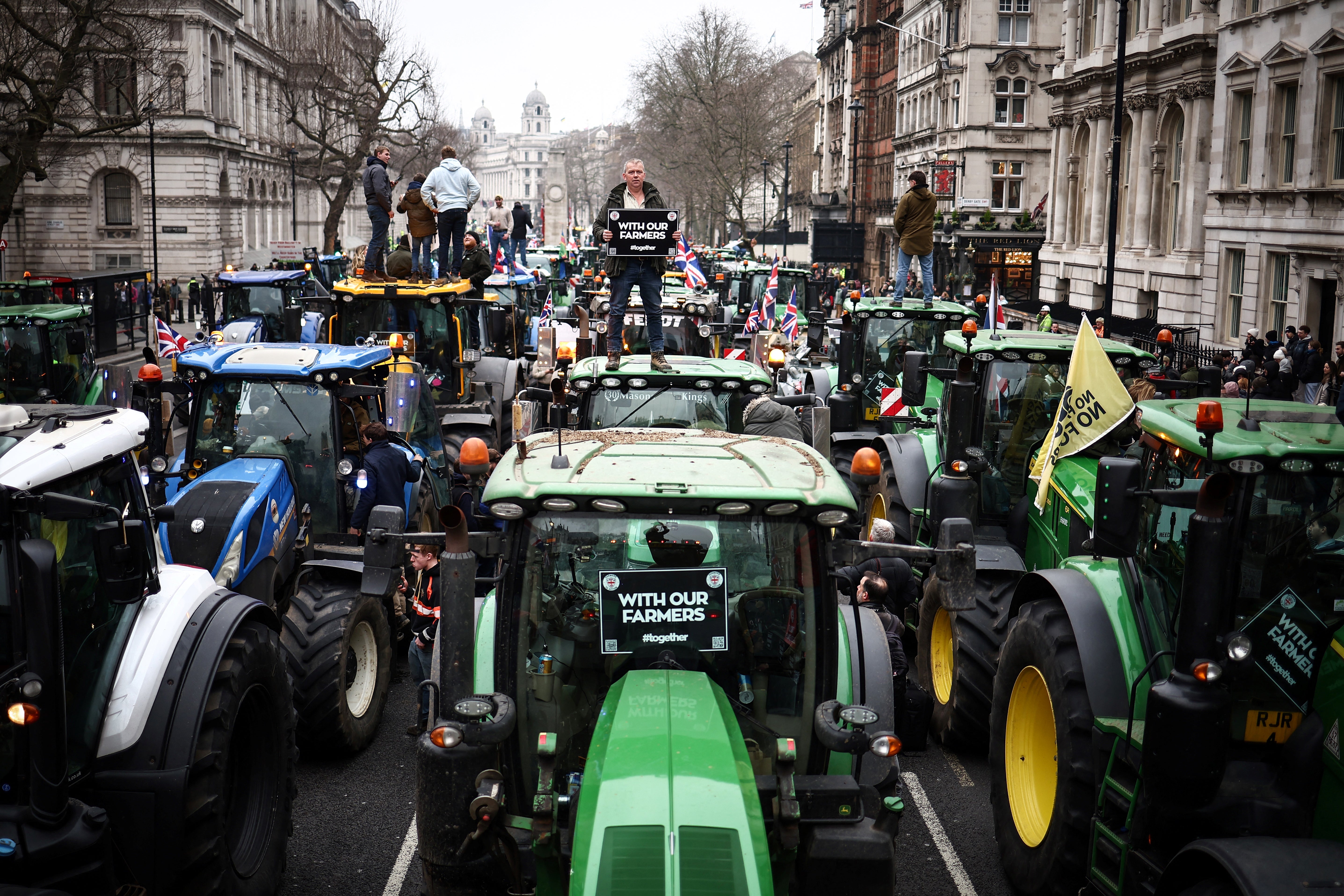 <p>Farmers standing on their tractors as they attend a rally in Westminster </p>