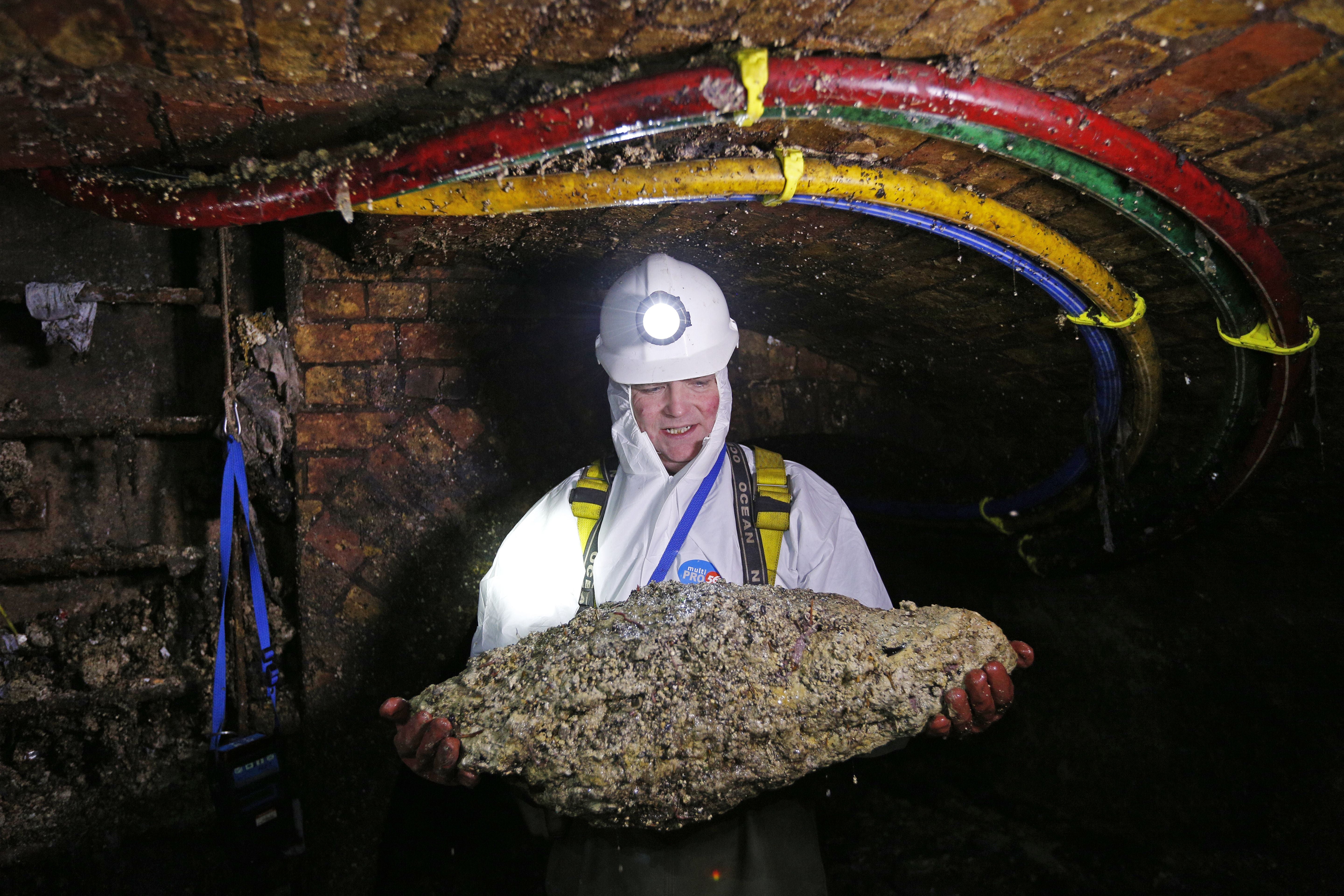 A trunk sewer technician holds a 'fatberg' taken from a sewer in London in December 2014