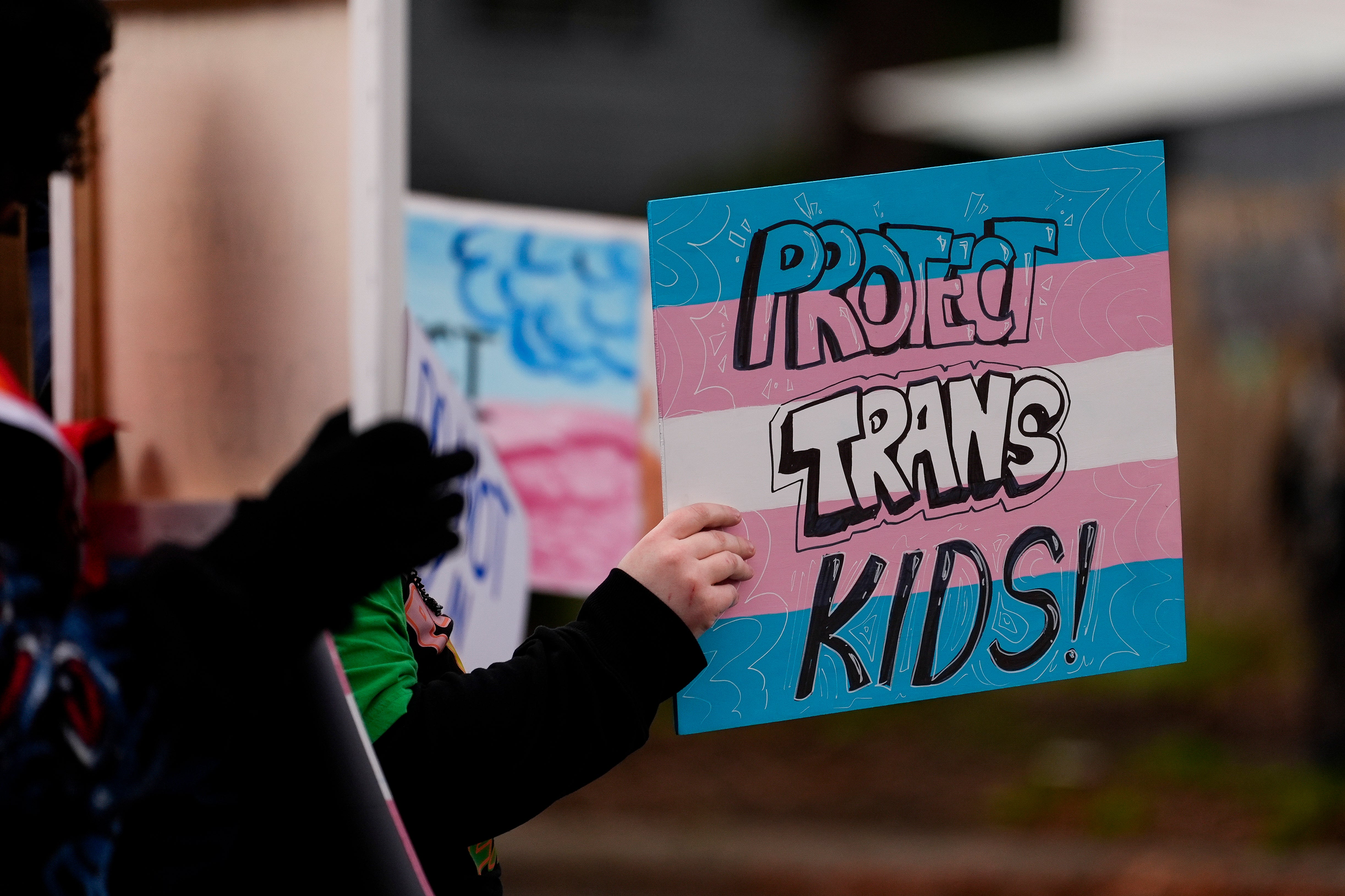 A person holds a sign during a pro-transgender rights protest outside of Seattle Children's Hospital after the institution postponed some gender-affirming surgeries for minors following an executive order by President Donald Trump.