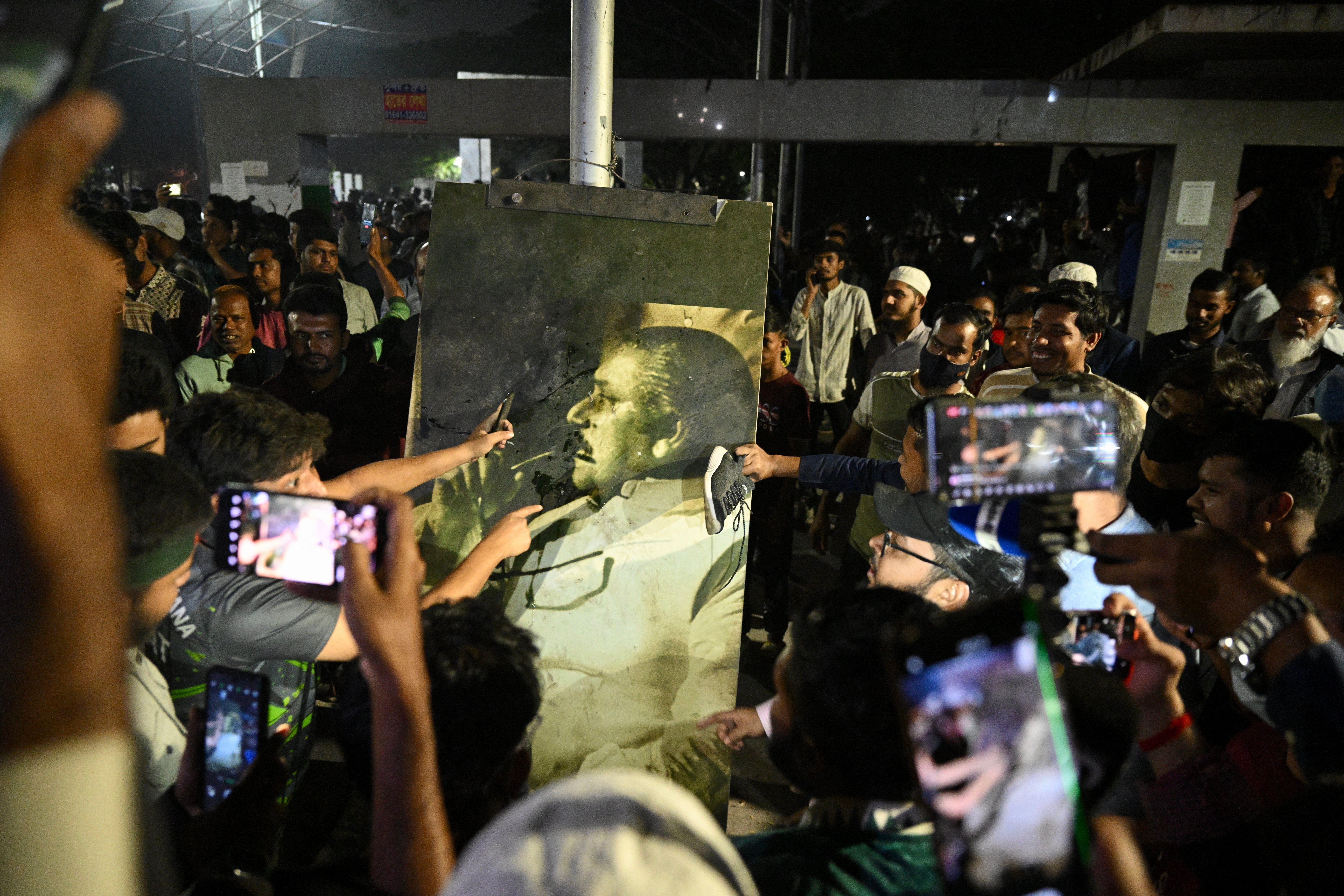 Protesters throw shoes at a portrait of Sheikh Mujibur Rahman, father of the former prime minister Sheikh Hasina, as they storm his former residence the Bangabandhu Memorial Museum, in Dhaka on 5 February 2025