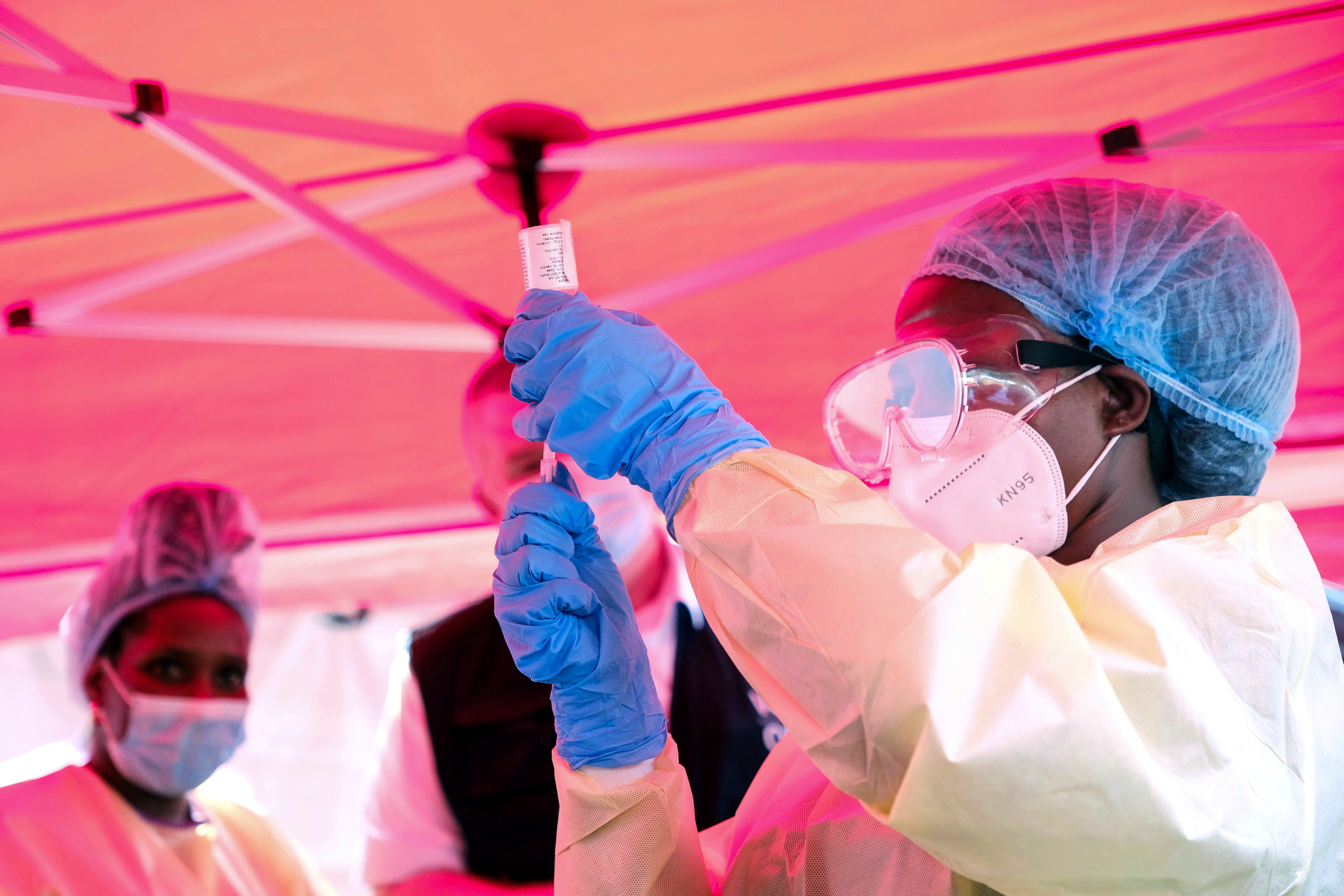 A health worker prepares to administer a vial of a vaccine against the Sudan strain of Ebola