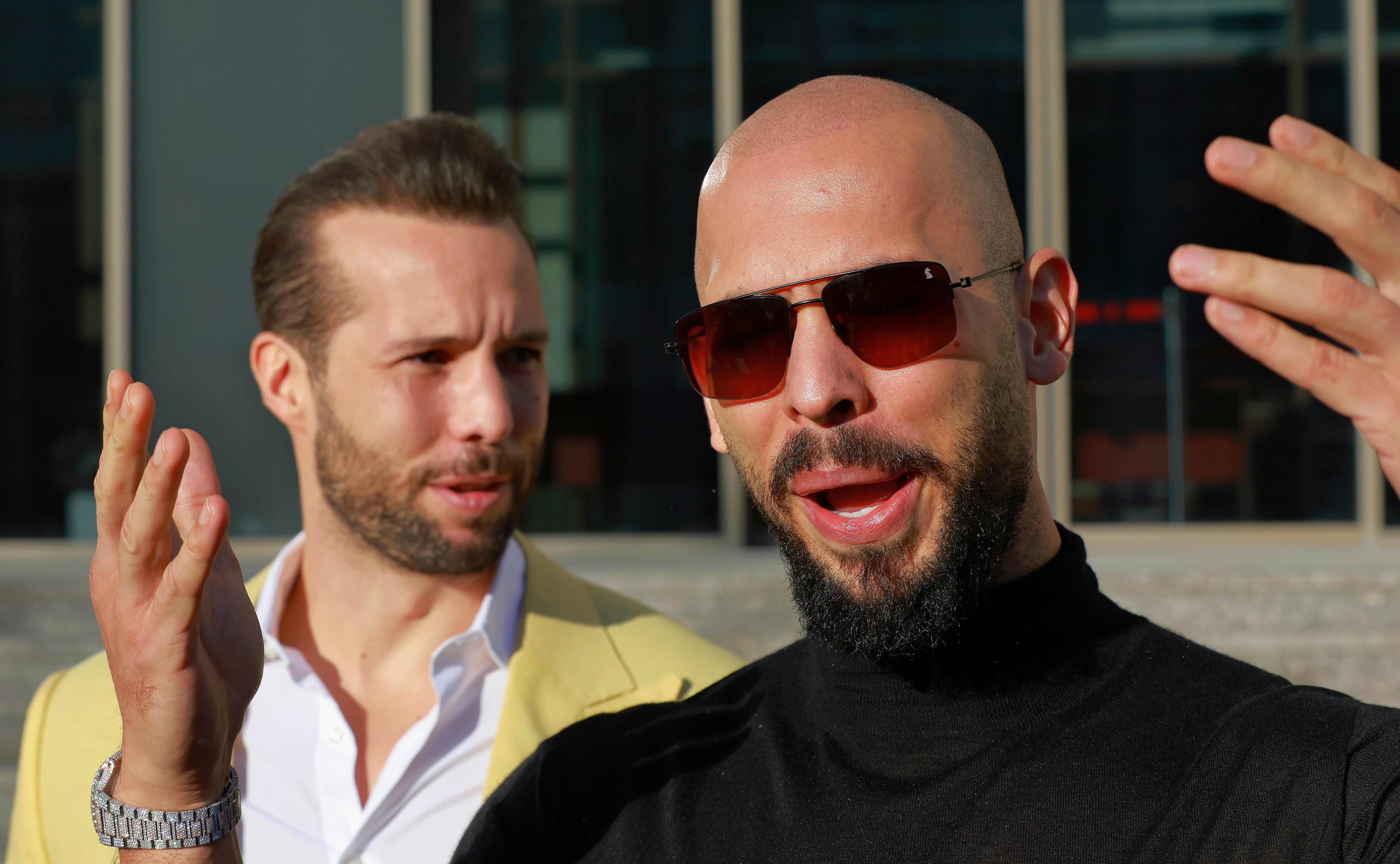 Andrew Tate, backed by his brother Tristan, gestures while mocking media reporters after a hearing on return of confiscated goods at Bucharest Court in Romania on January 9. An American woman accused the brothers of recruiting her to participate in sex work after 'luring' her to Romania in the first suit brought against the brothers in the U.S.