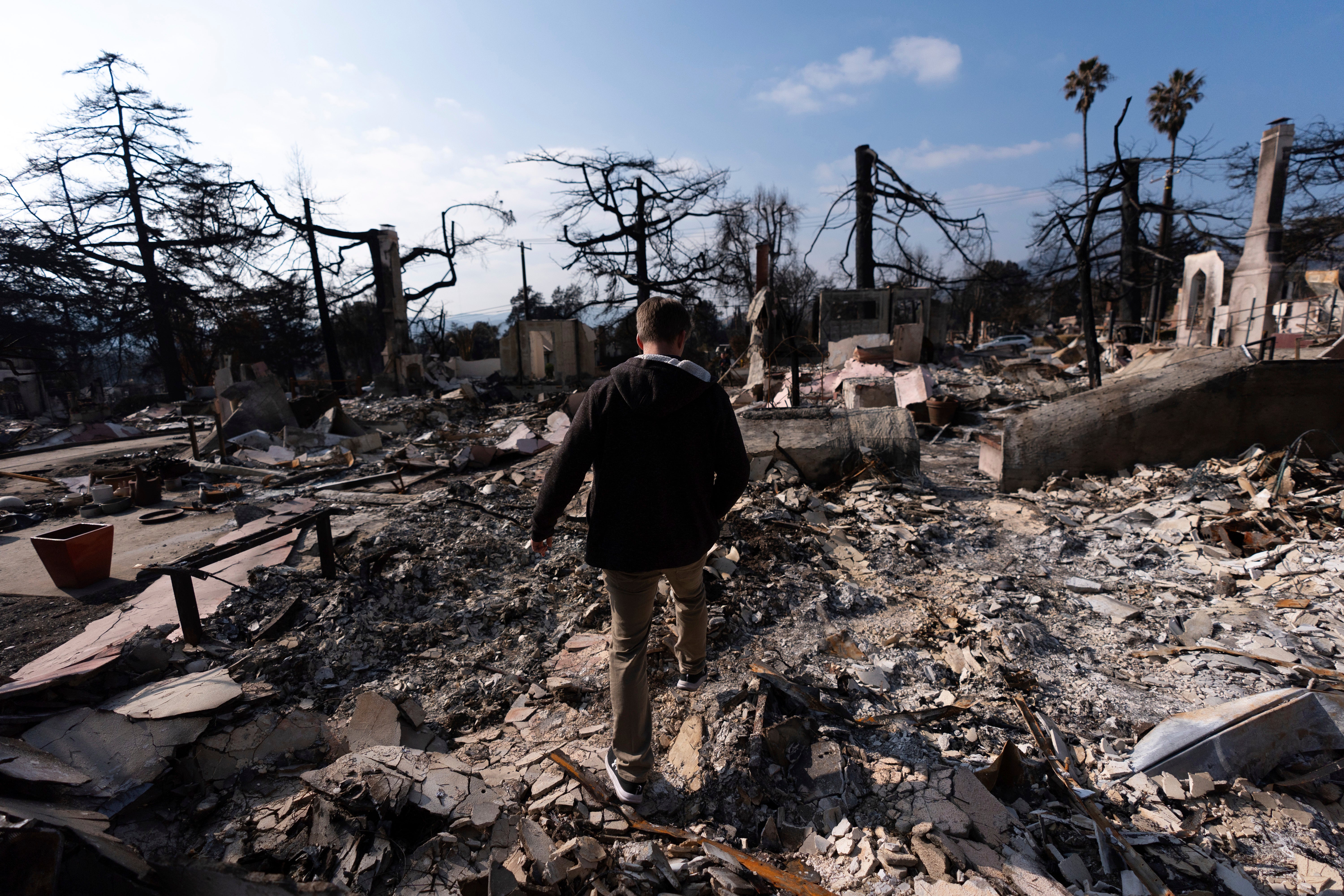 <p>Chris Wilson walks through the remains of his home, consumed by the Eaton Fire, in Altadena</p>