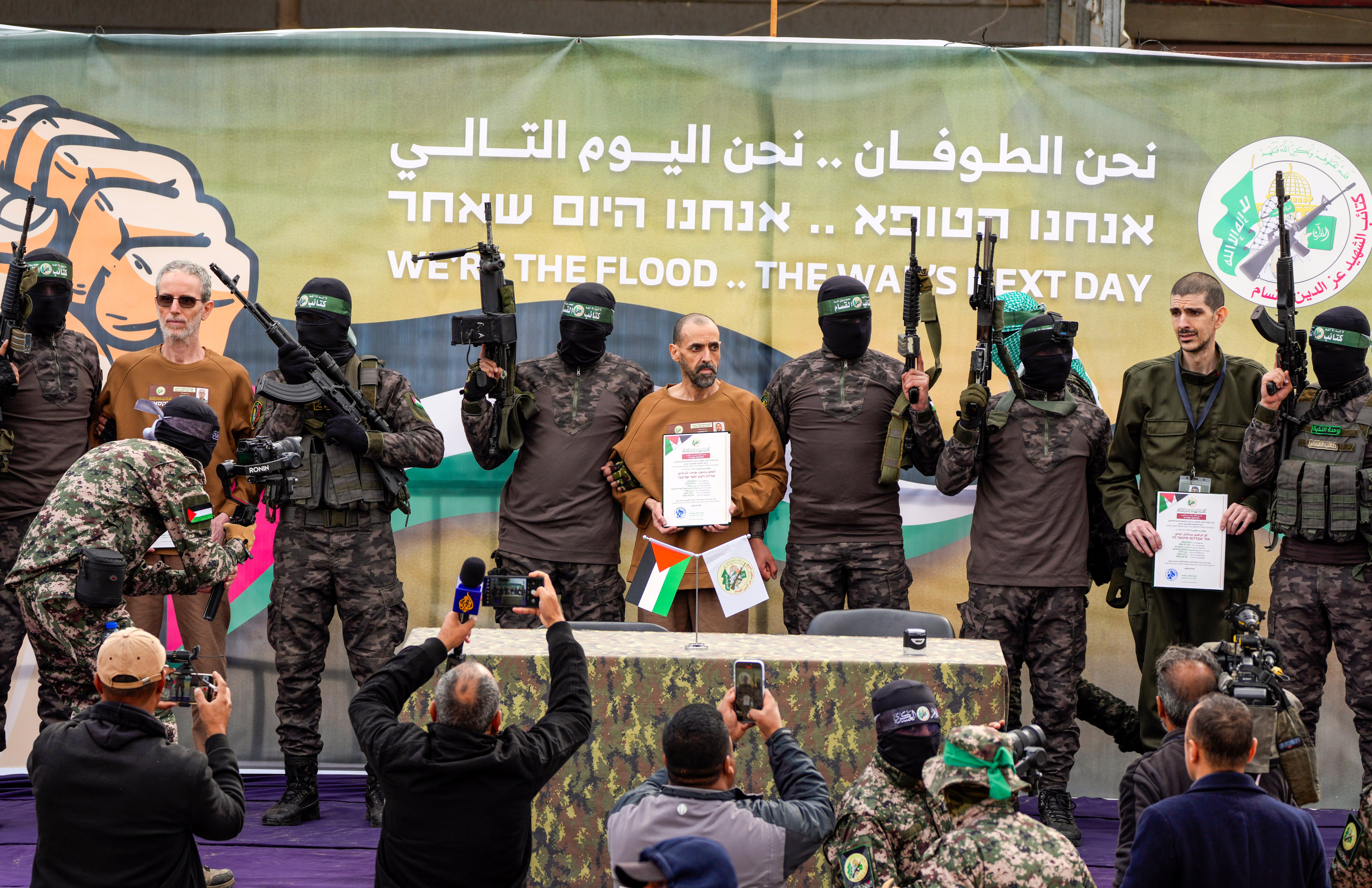 Israeli captives, from left to the right, Ohad Ben Ami, Eli Sharabi and Or Levy, who have been held hostage by Hamas in Gaza since Oct. 7, 2023, are escorted by Hamas fighters on a stage before being handed over to the Red Cross in Deir al-Balah