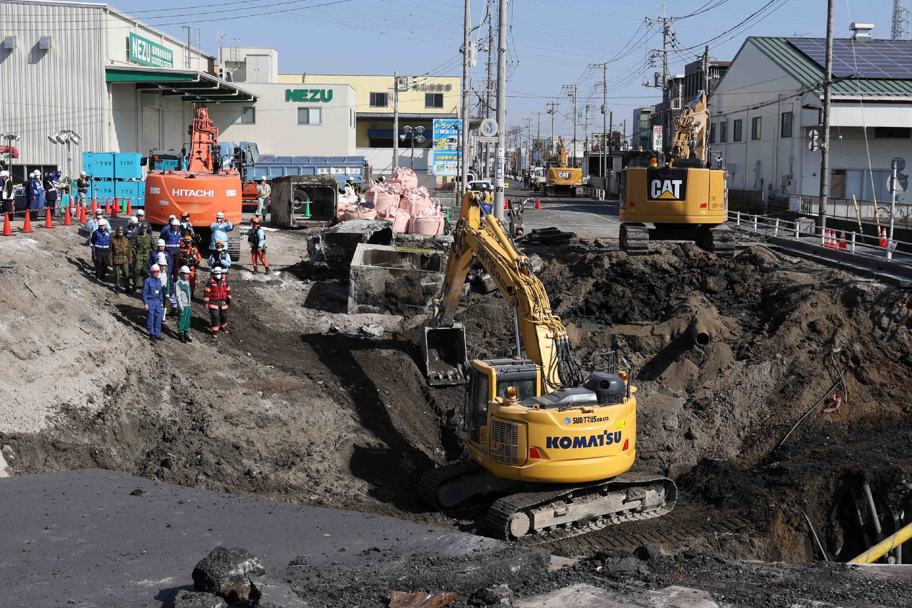 <p>Excavators and rescue personnel working to construct a slope for rescue operations are seen at the site where a truck on 28 January plunged into a sinkhole, trapping the vehicle's driver, in Yashio, Saitama Prefecture</p>