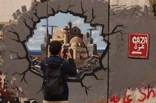 Man takes a graffiti photo representing the reconstruction of Gaza