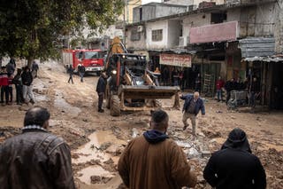 Bulldozers clean up mud and debris along the destroyed street