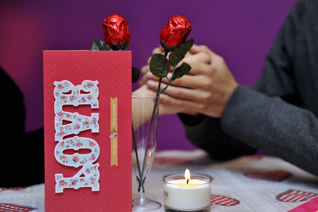 Picture posed by models of a couple with valentines gifts of a card, chocolates and chocolate roses in a glass (Nicholas T Ansell/PA)