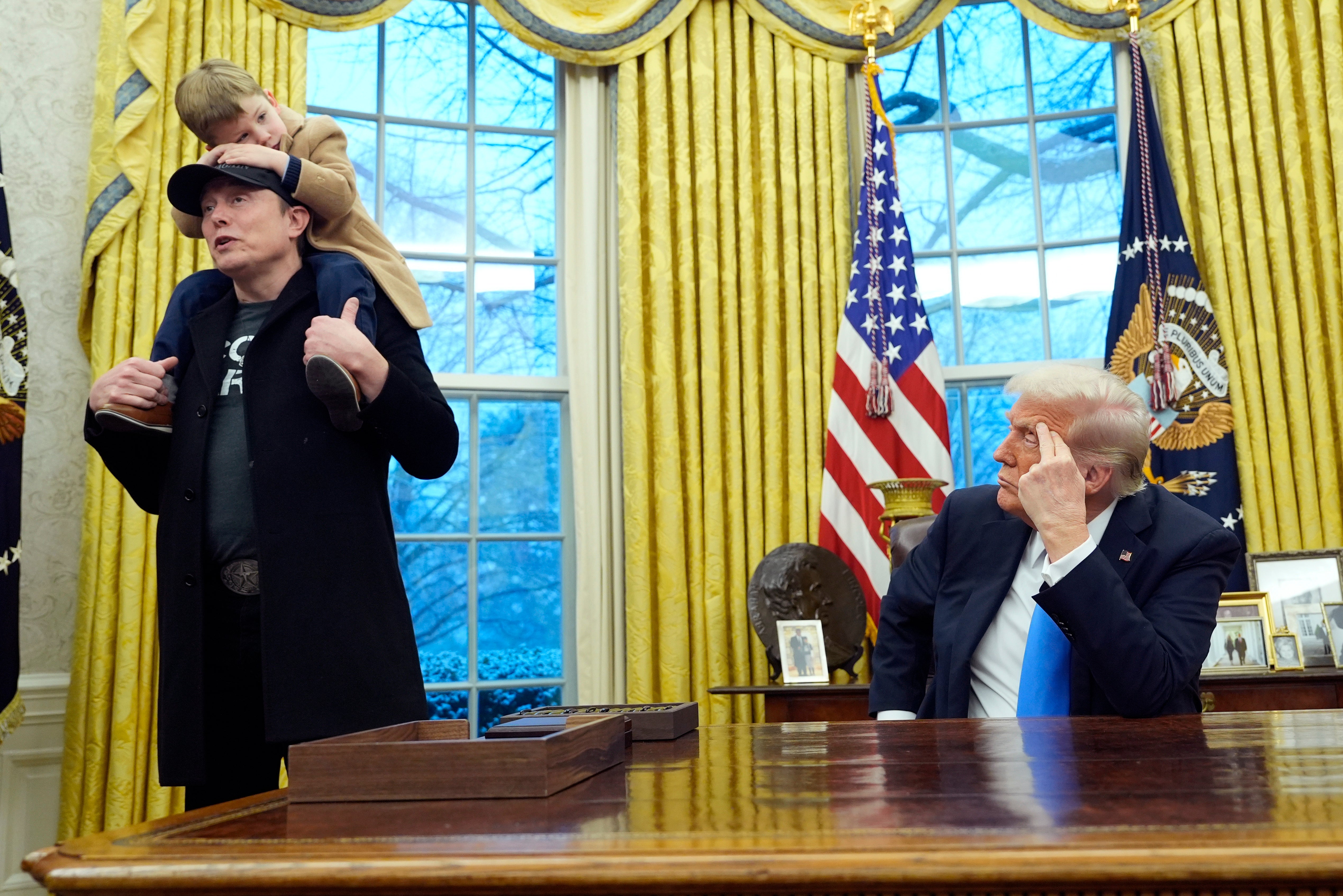 President Donald Trump listens as Elon Musk, joined by his son X Æ A-Xii, speaks in the Oval Office at the White House