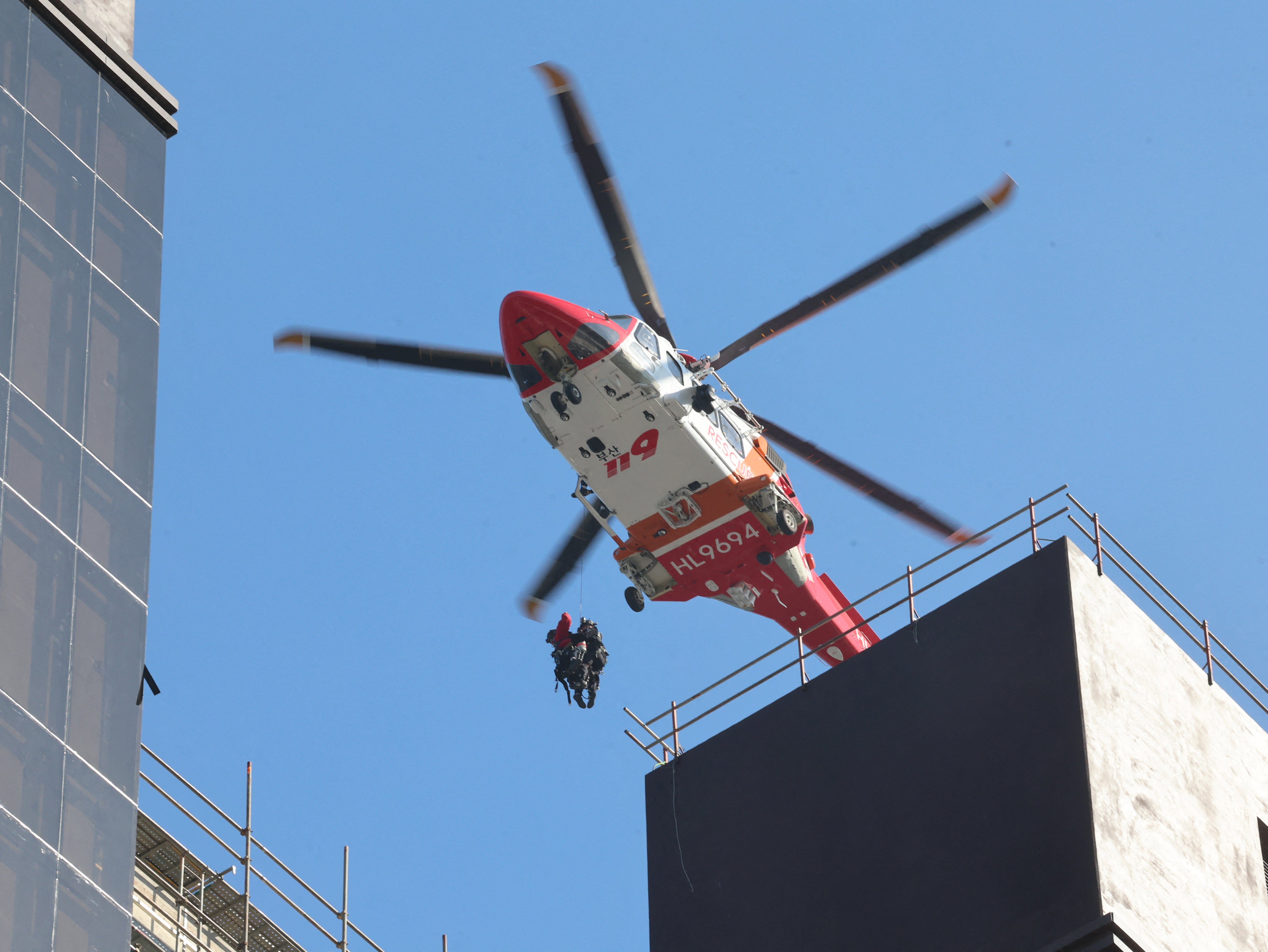 A rescue helicopter carries evacuees from the rooftop at the scene of a fire at a construction site of the Banyan Tree Hotel in the southern port city of Busan on February 14, 2025