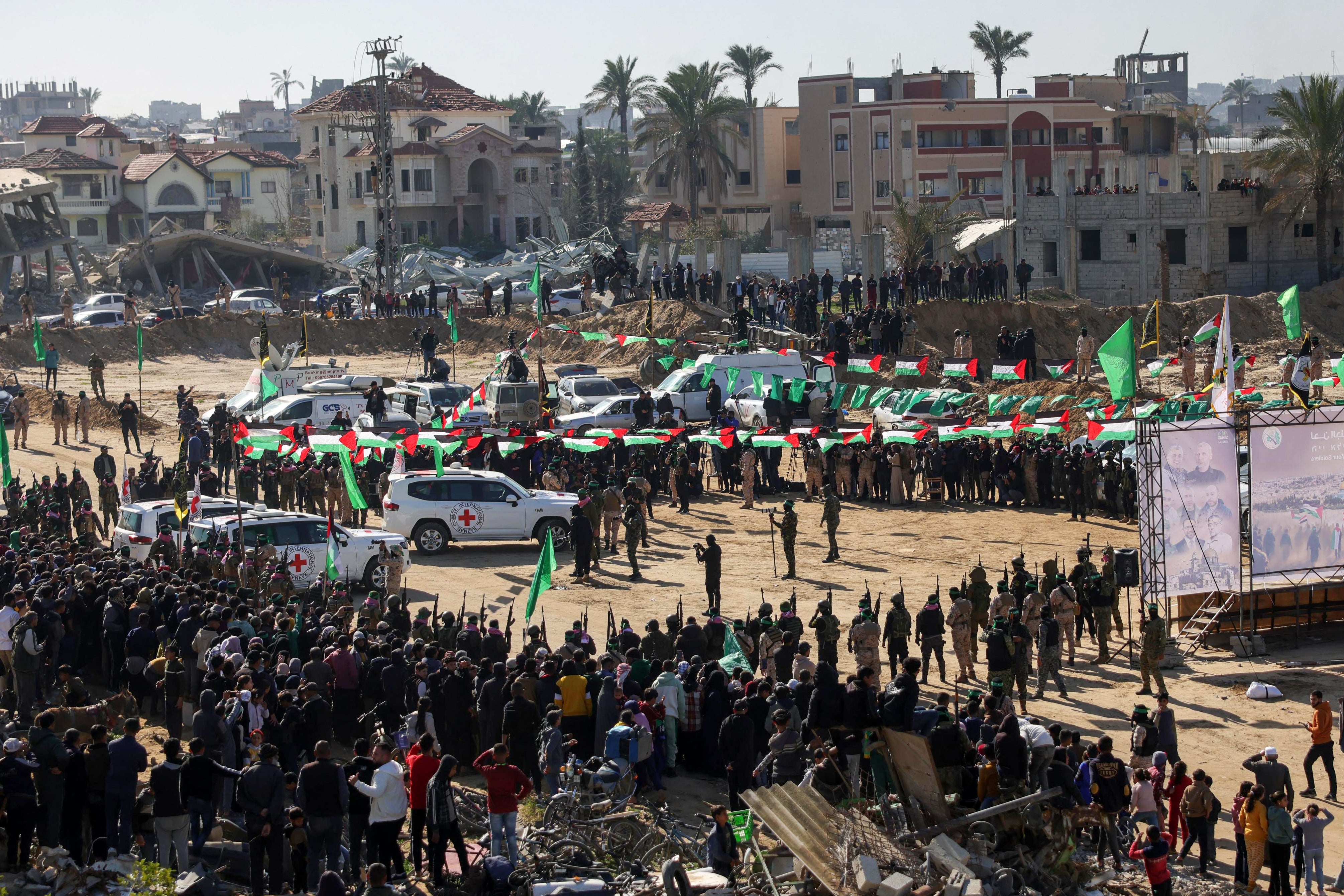 Red Cross vehicles wait at the spot where Hamas militants handed over Israeli hostages on Saturday