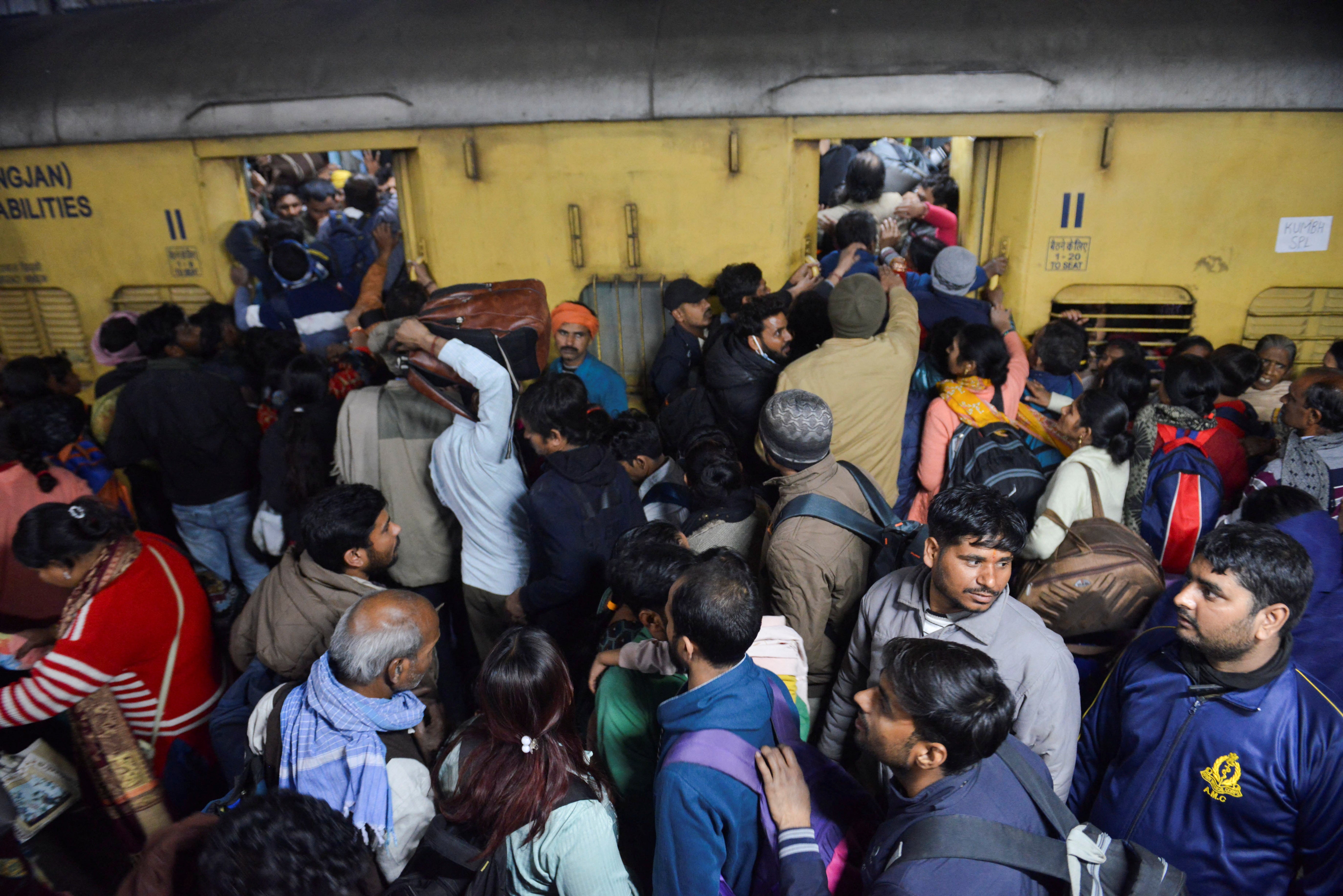 Passengers, including Hindu pilgrims on their way to attend Maha Kumbh Mela, jostle to board a train at the New Delhi railway station