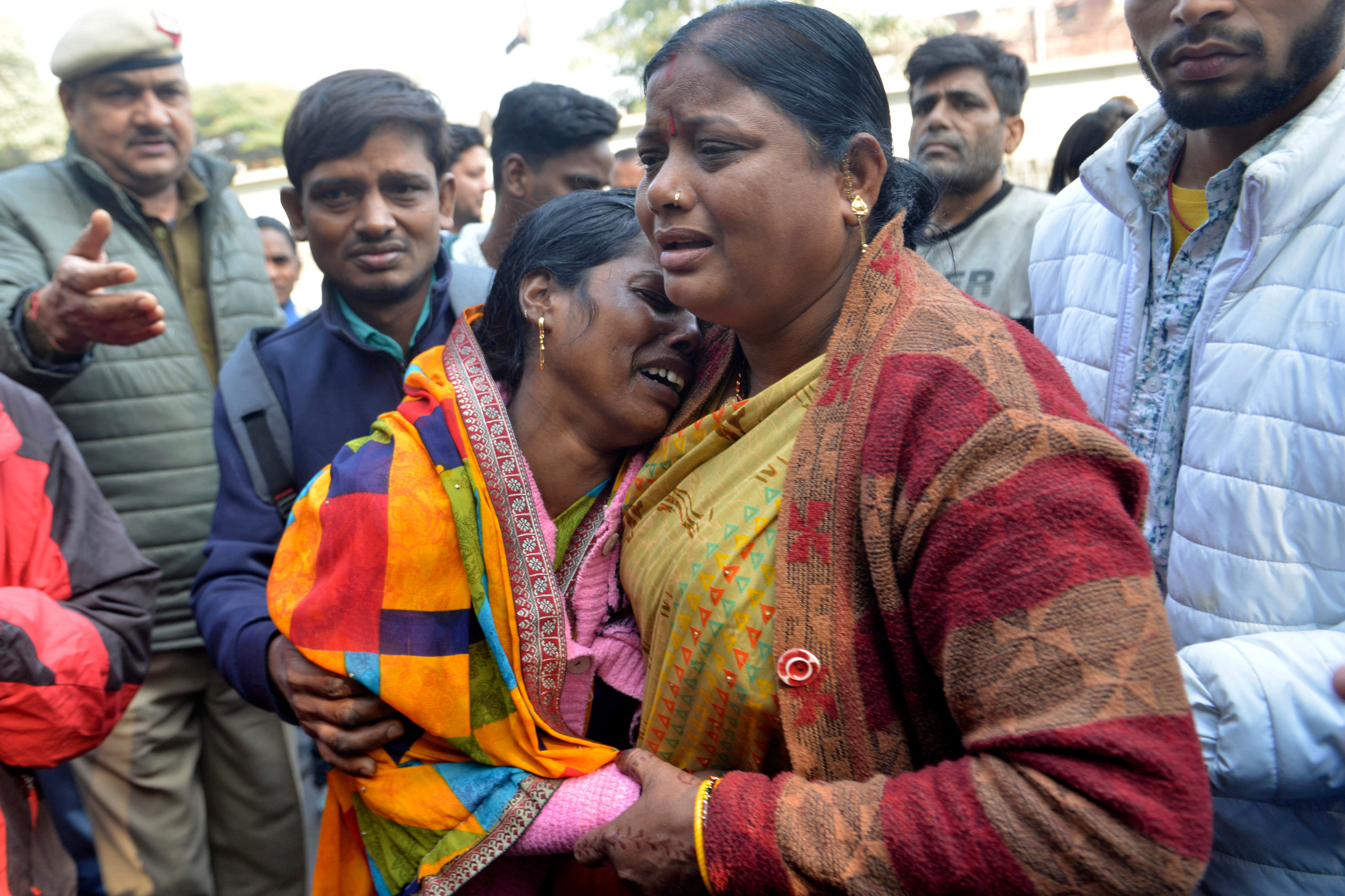 Relatives of a passenger who died during a stampede took place Saturday at New Delhi railway station, console each other as they wait to collect the body from a hospital