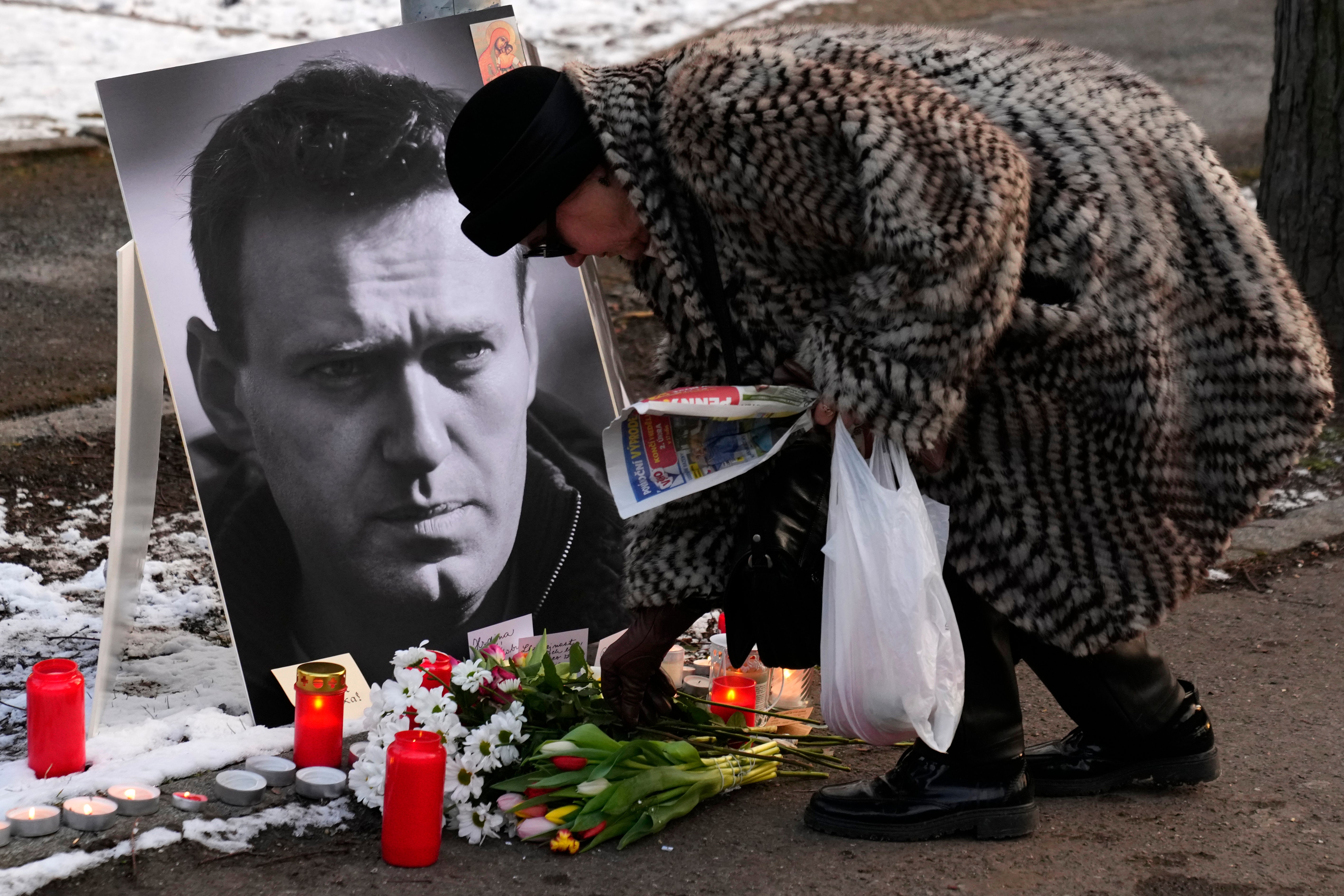 A woman places flowers by a photograph of Russian opposition leader Alexei Navalny