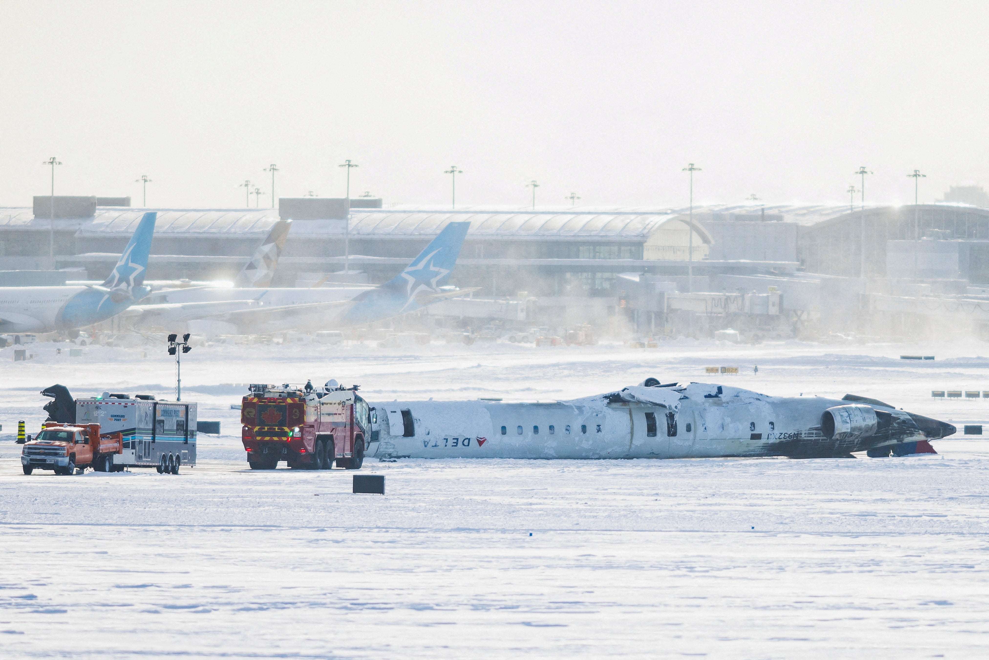 The wreckage of Delta Flight 4819 on a snow-covered runway. One passenger said those on board were left hanging from their seatbelts ‘like bats’ as the plane came to a stop while flipped on its roof