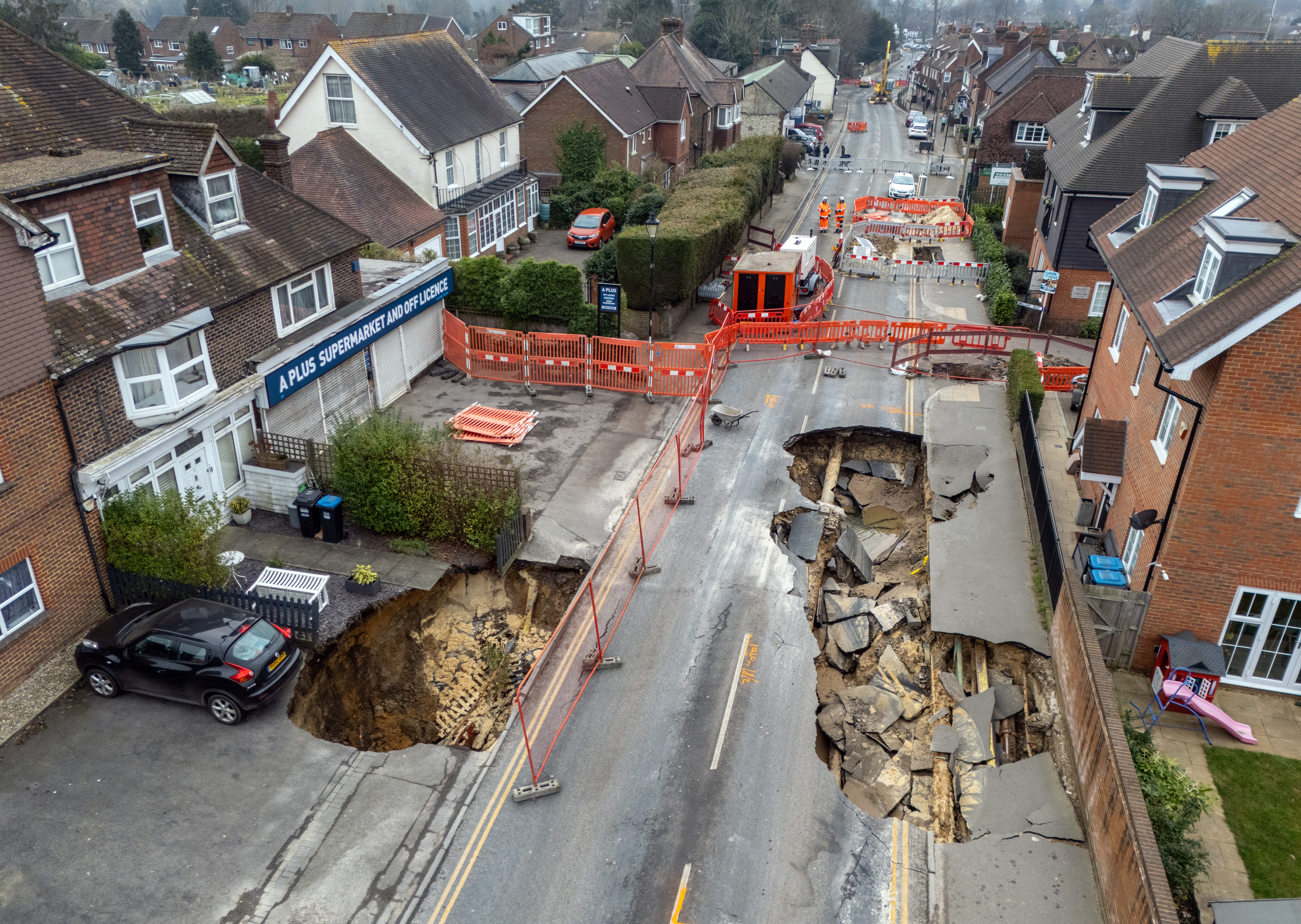 <p>A second sinkhole shows a car teetering next to it </p>