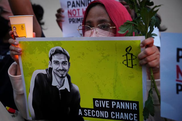 <p>An activist holds a candle and a placard during a vigil against the impending execution of Pannir Selvam Pranthaman for trafficking heroin into Singapore, outside the Singaporean embassy in Kuala Lumpur, Malaysia</p>