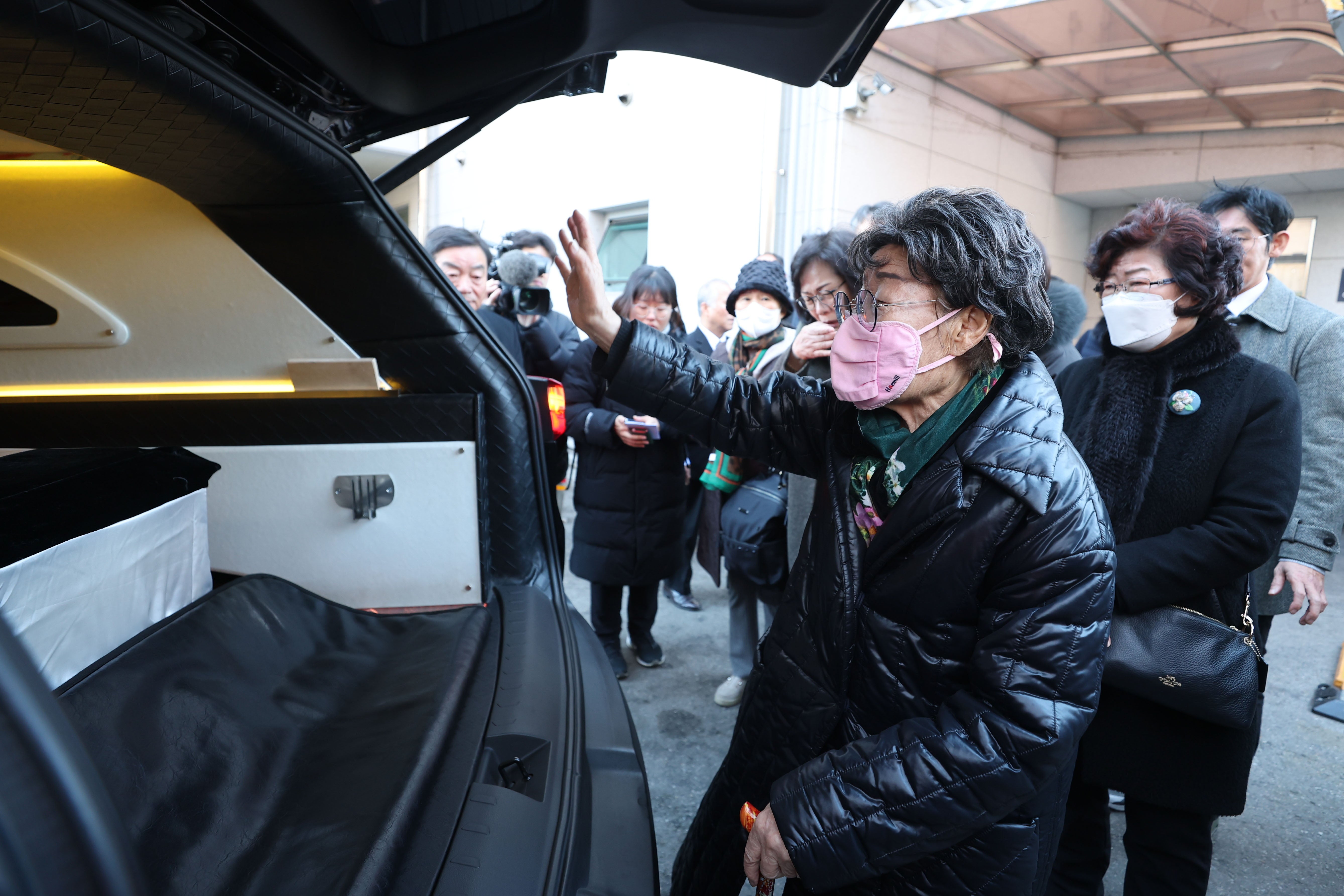 Lee Yong-soo, an outspoken South Korean victim of Japan's wartime military sexual slavery, euphemistically called 'comfort women,' waves in front of a hearse carrying the coffin of Gil Won-ok