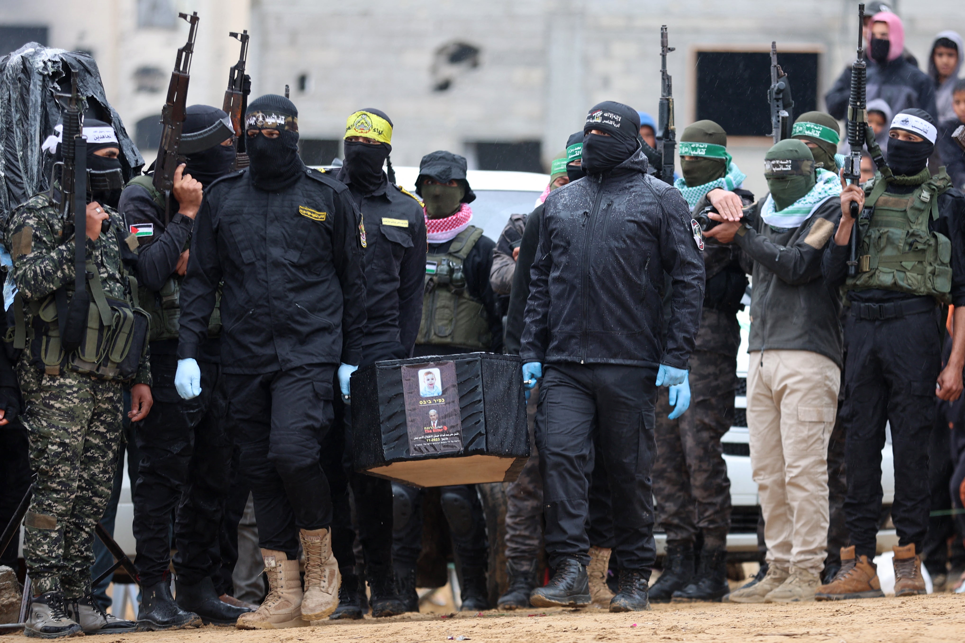 Militantes palestinos carregam um dos quatro caixões em quatro cadáveres de reféns israelenses em fevereiro de 2025, em 2025, na mão de South Gaza Khan carregando a mão nas mãos da Cruz Vermelha para a Cruz Vermelha de South Gaza