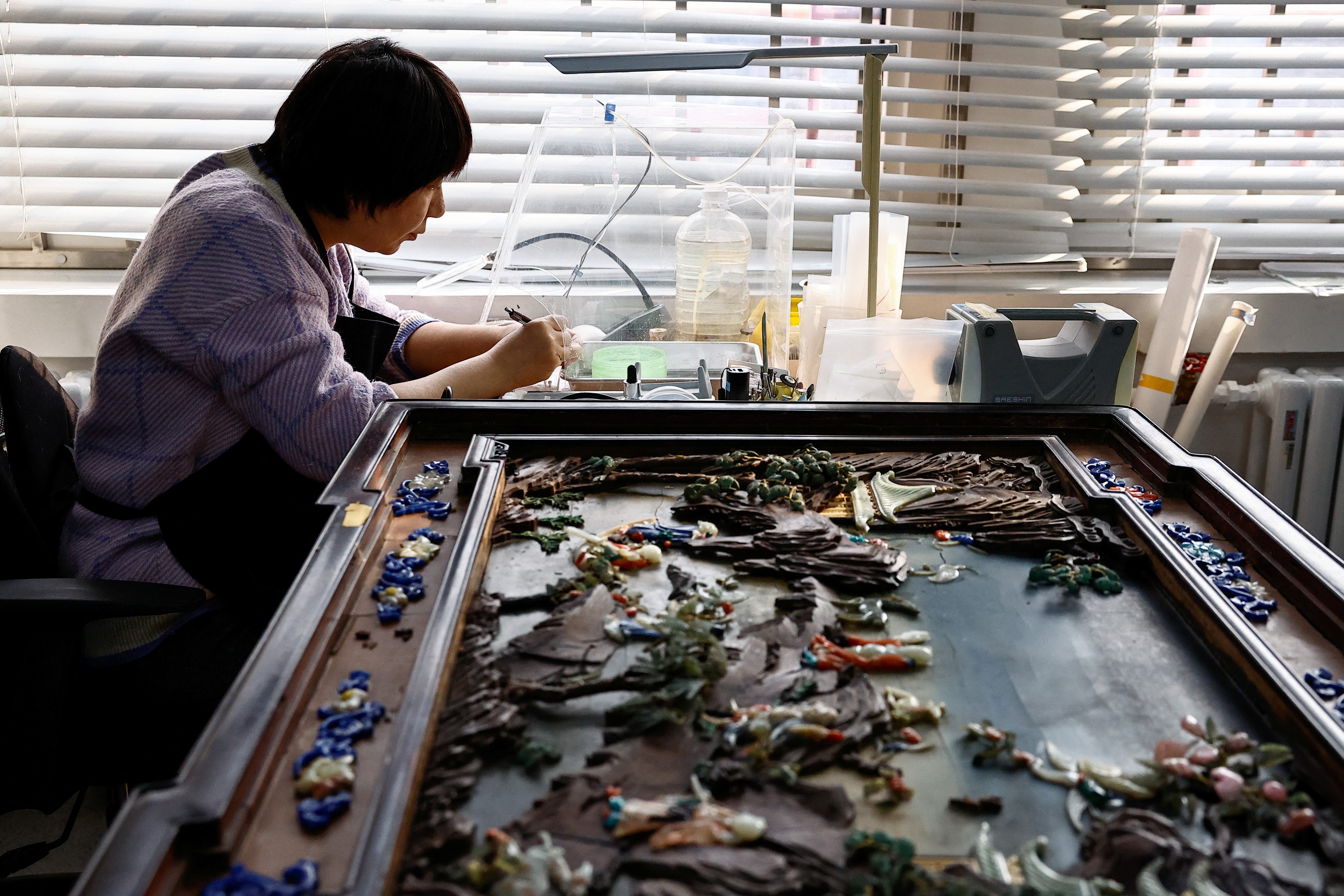 A conservator restores a cultural relic at the cultural protection and restoration department of the Palace Museum at the Forbidden City