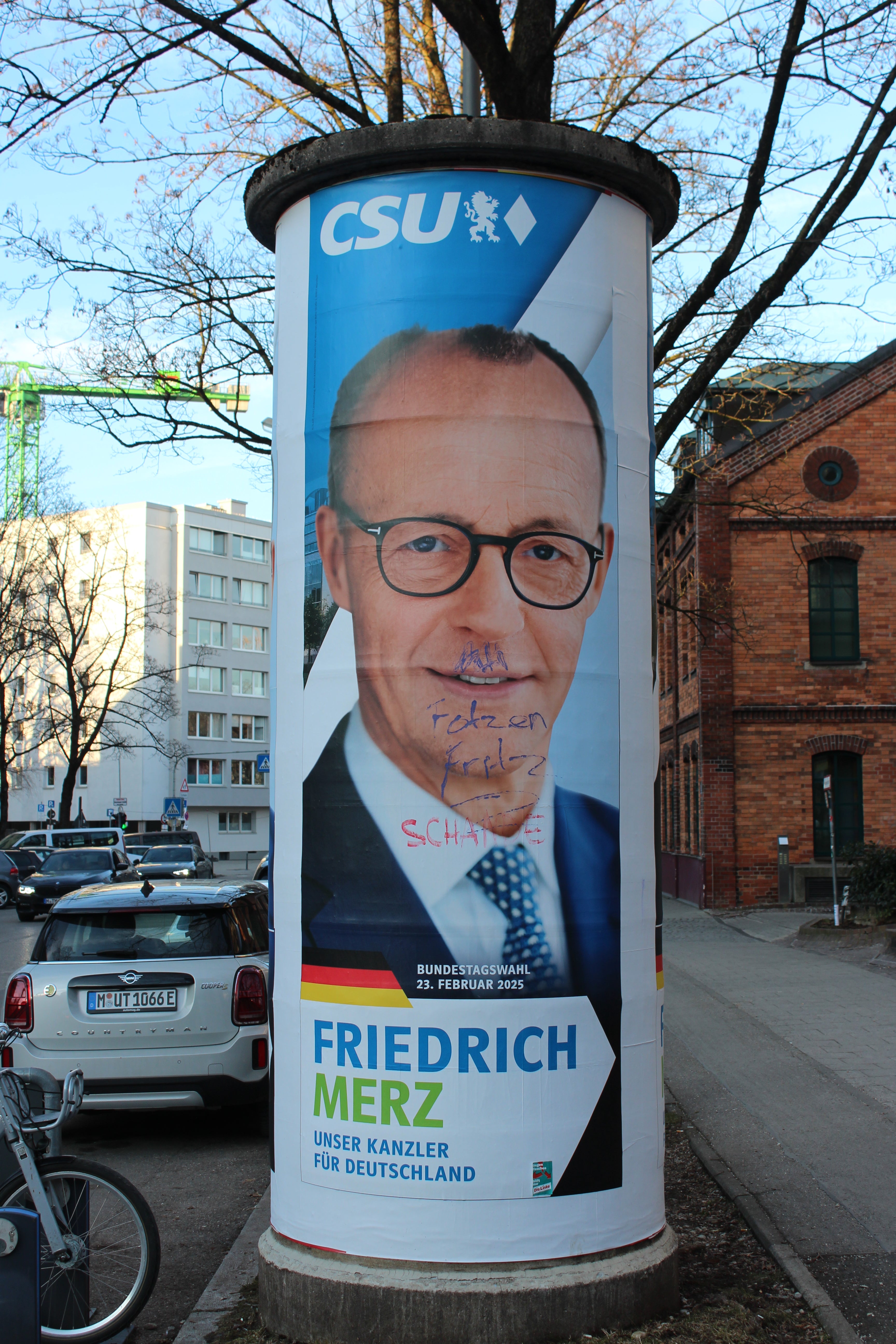 A poster of Friedrich Merz is defaced with an Adolf Hitler moustache near the scene of the Munich attack