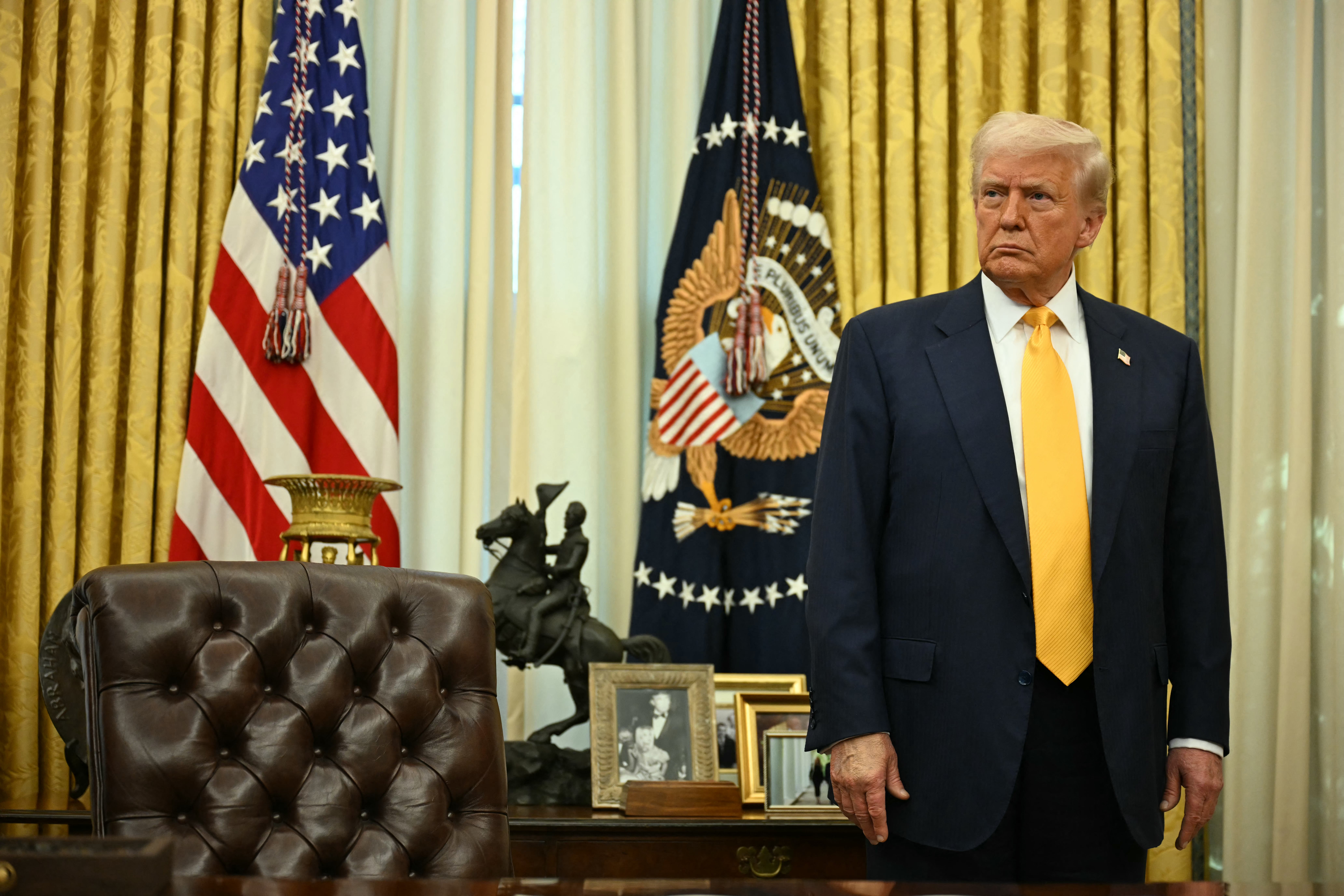 US President Donald Trump stands behind the Resolute Desk during a ceremonial swearing-in for US Secretary of Commerce Howard Lutnick in the Oval Office of the White House in Washington, DC, on February 21, 2025