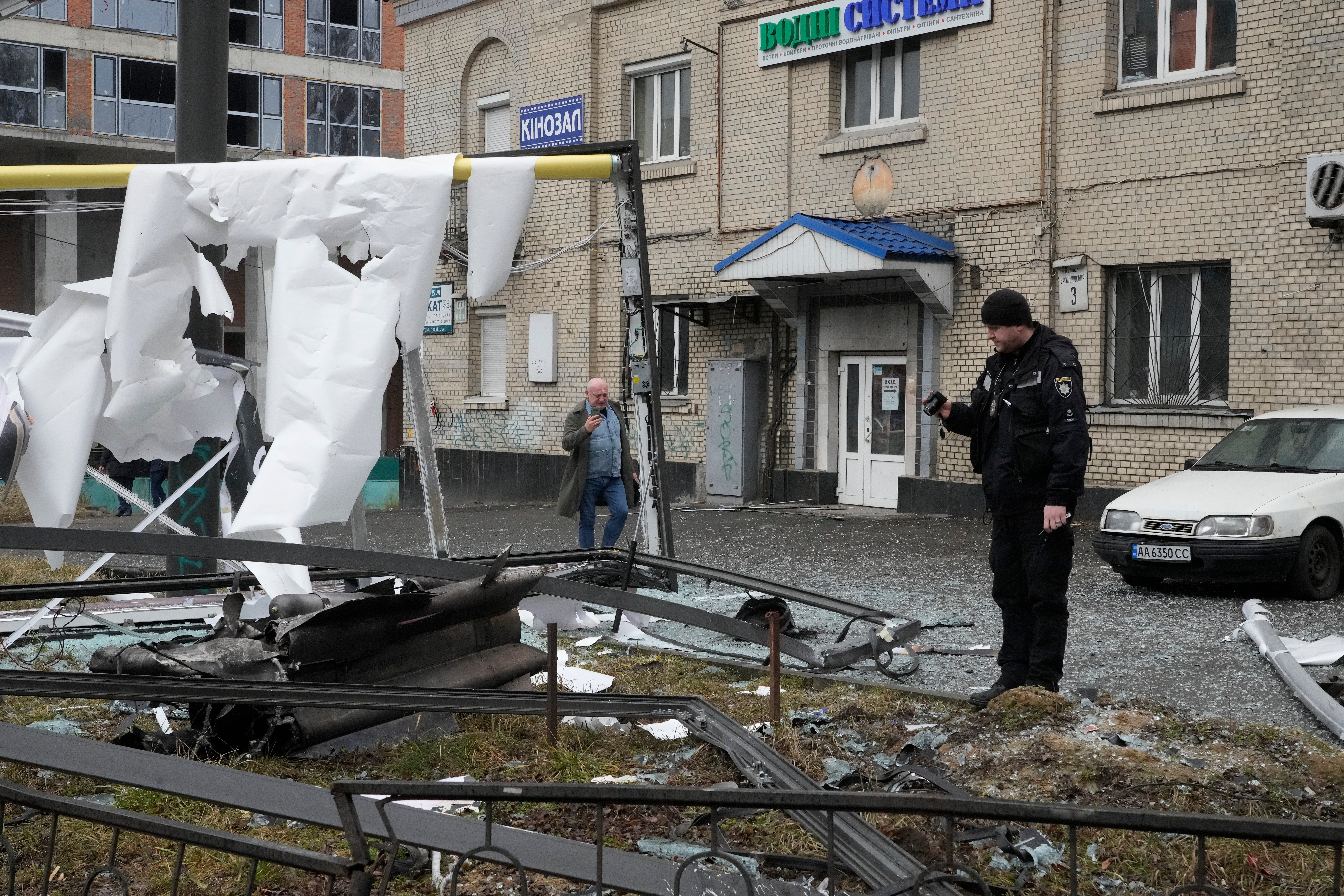 A police officer takes a photo of the consequences of a Russian strike in Kyiv, Ukraine, Thursday, Feb. 24, 2022