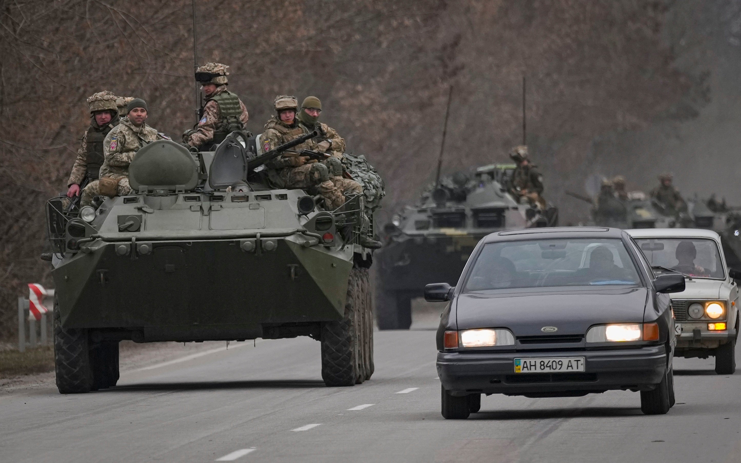<p>Ukrainian servicemen sit atop armoured personnel carriers driving on a road in Ukraine’s eastern Donetsk region</p>