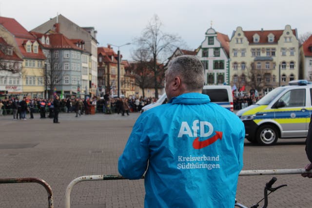 <p>An Alternative for Germany official stares across the Erfurt city square at counterprotesters </p>