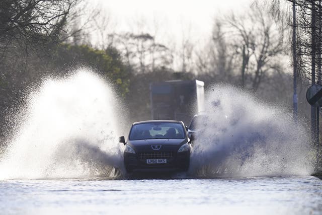 A vehicle drives through flood water (Danny Lawson/PA)