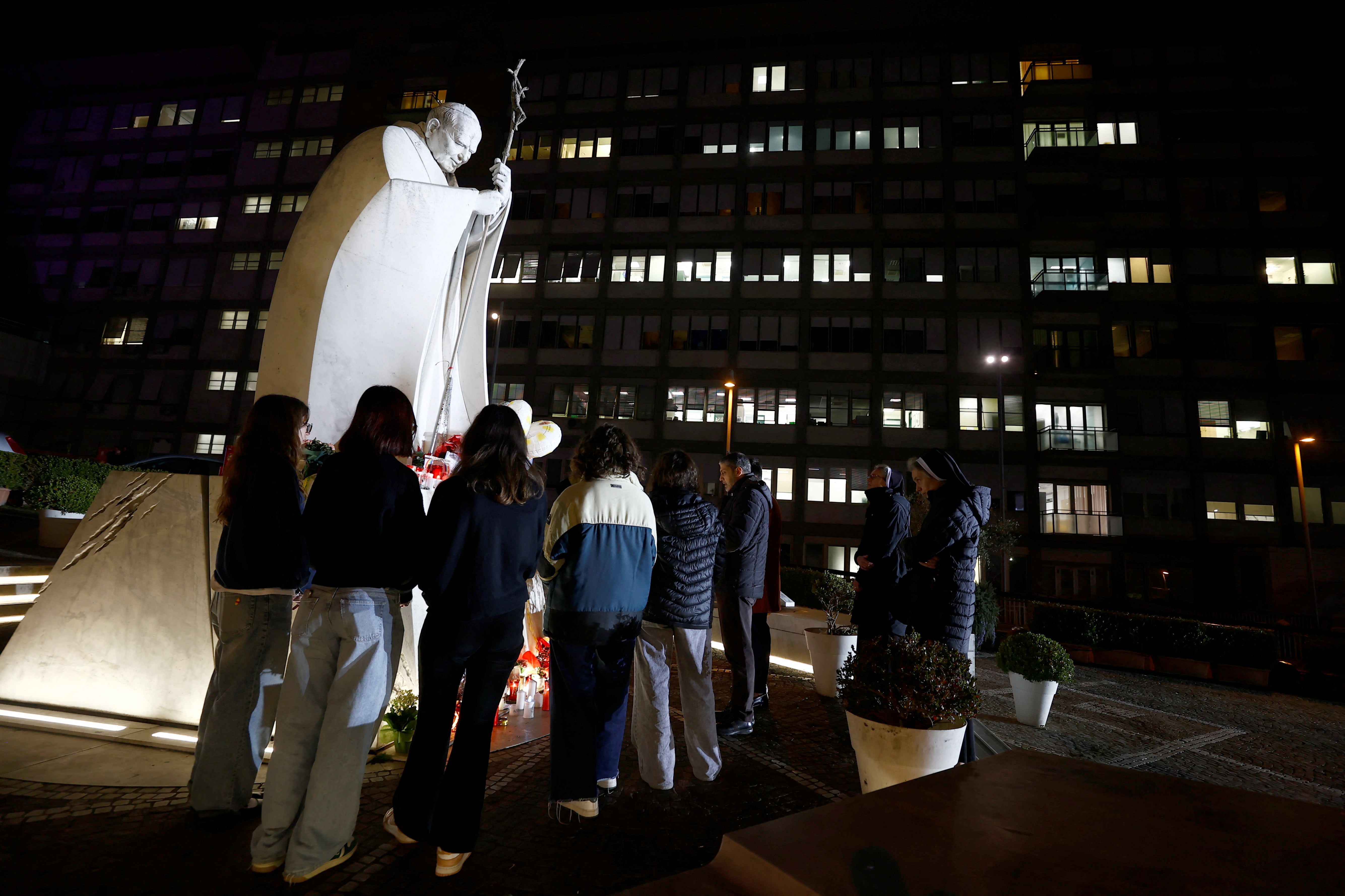 People pray outside the Gemelli Hospital in Rome on Sunday where Pope Francis is admitted for treatment