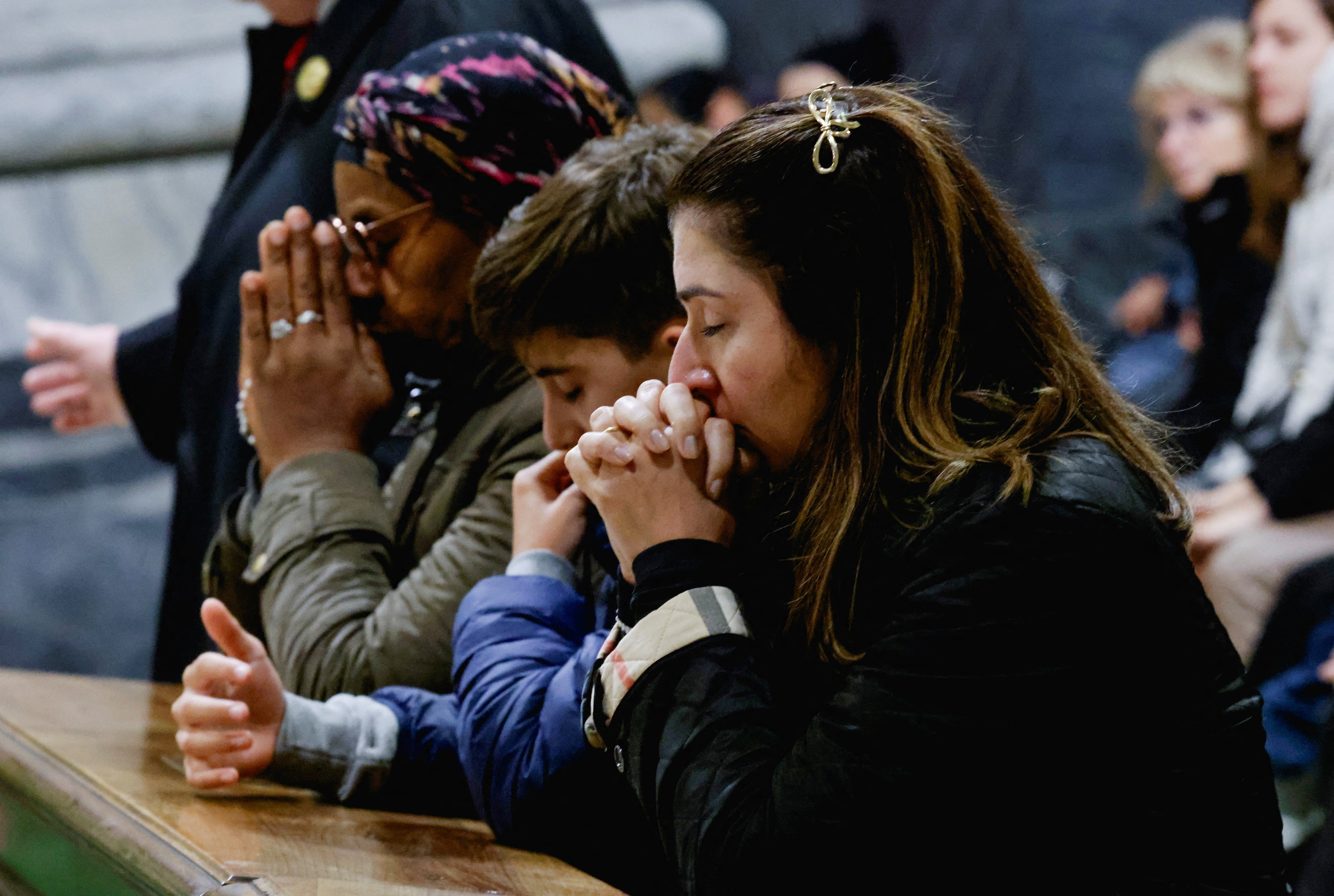 People pray for Pope Francis, who is in critical condition battling double pneumonia, inside St Peter's Basilica at the Vatican on Sunday