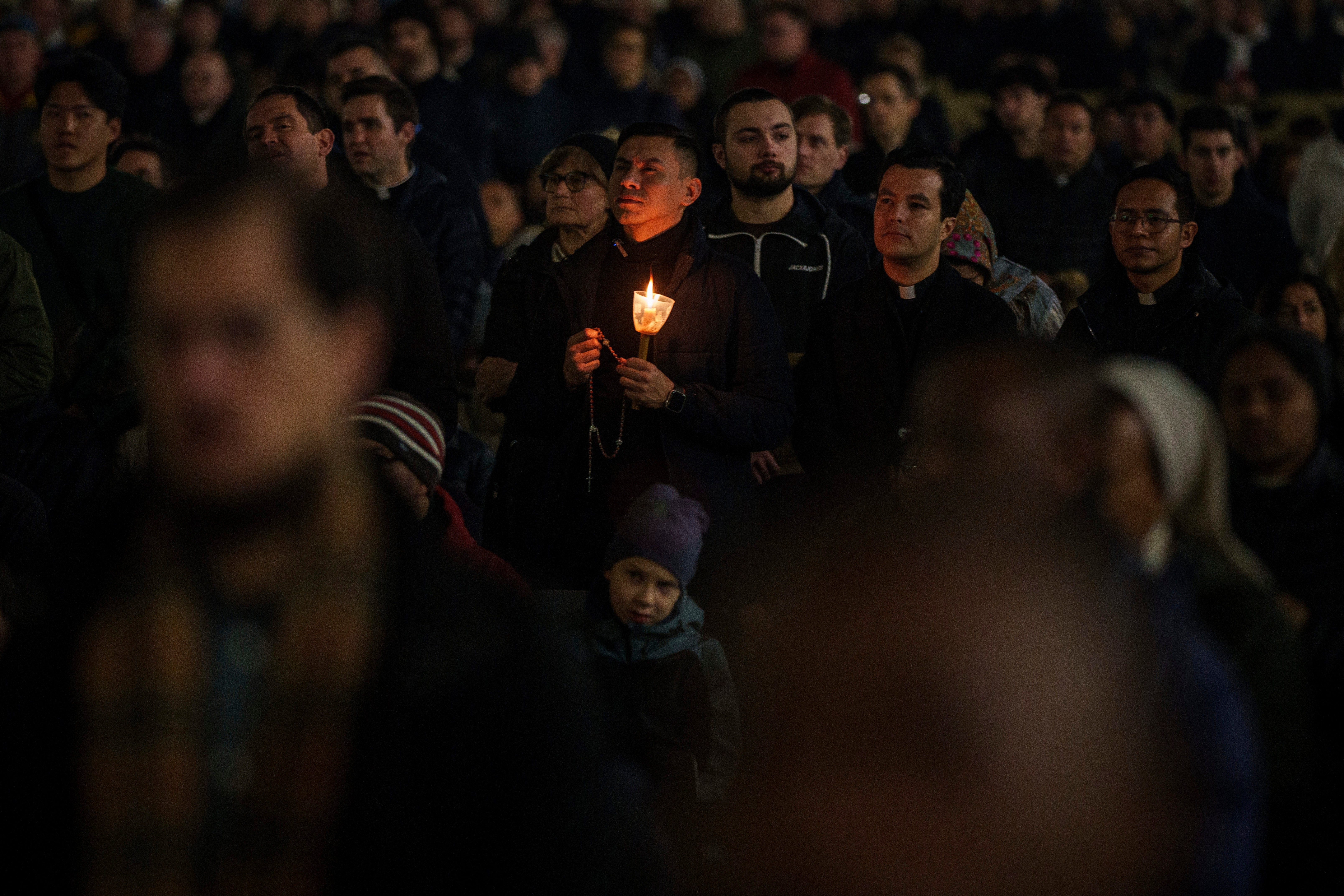 People attend a Rosary prayer service for the Pope at the Vatican on Monday