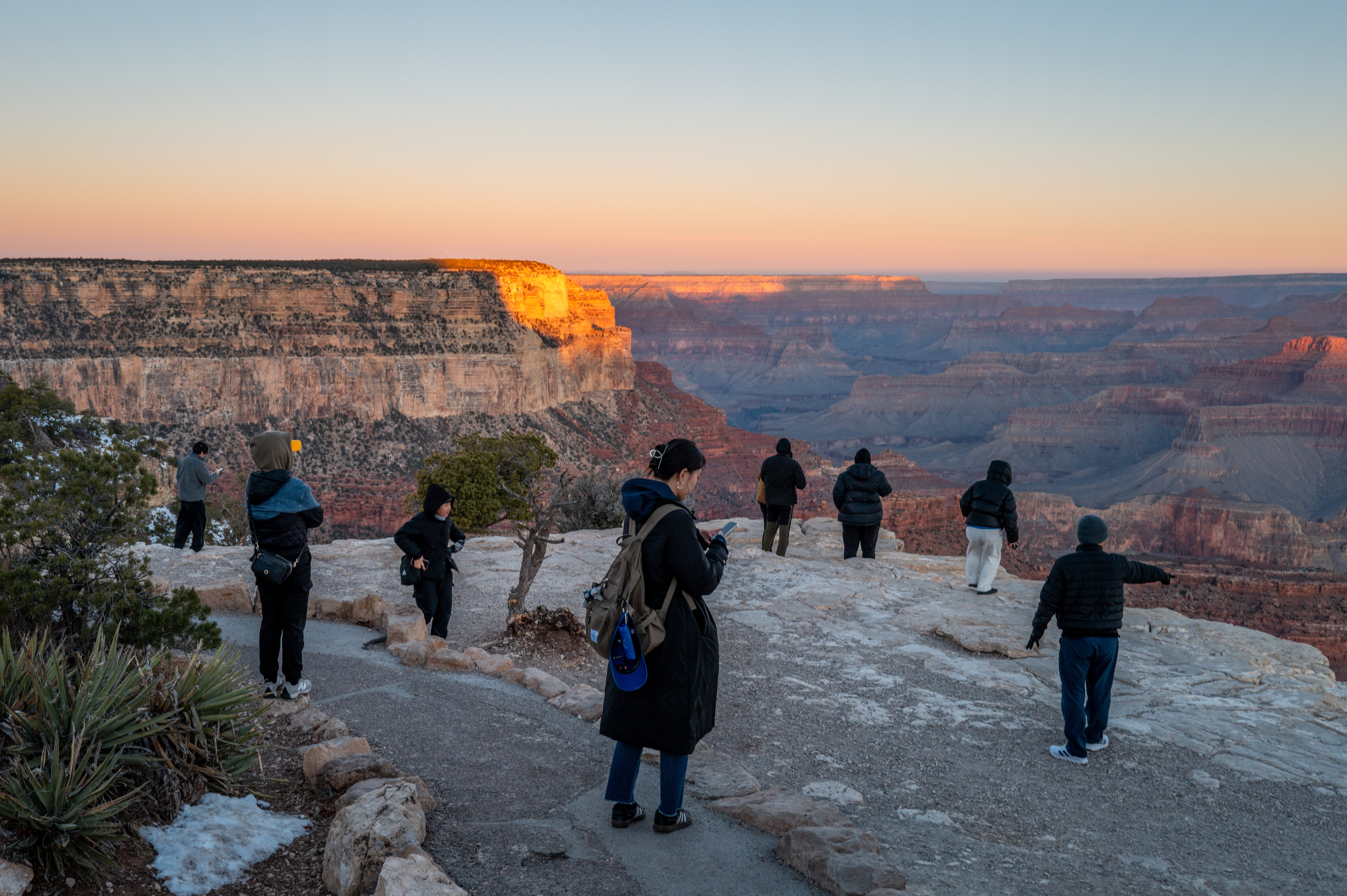 Tourists stand on the edge of the Grand Canyon in Arizona. The park has already seen consequences from the Trump administration’s layoffs in his return to the White House