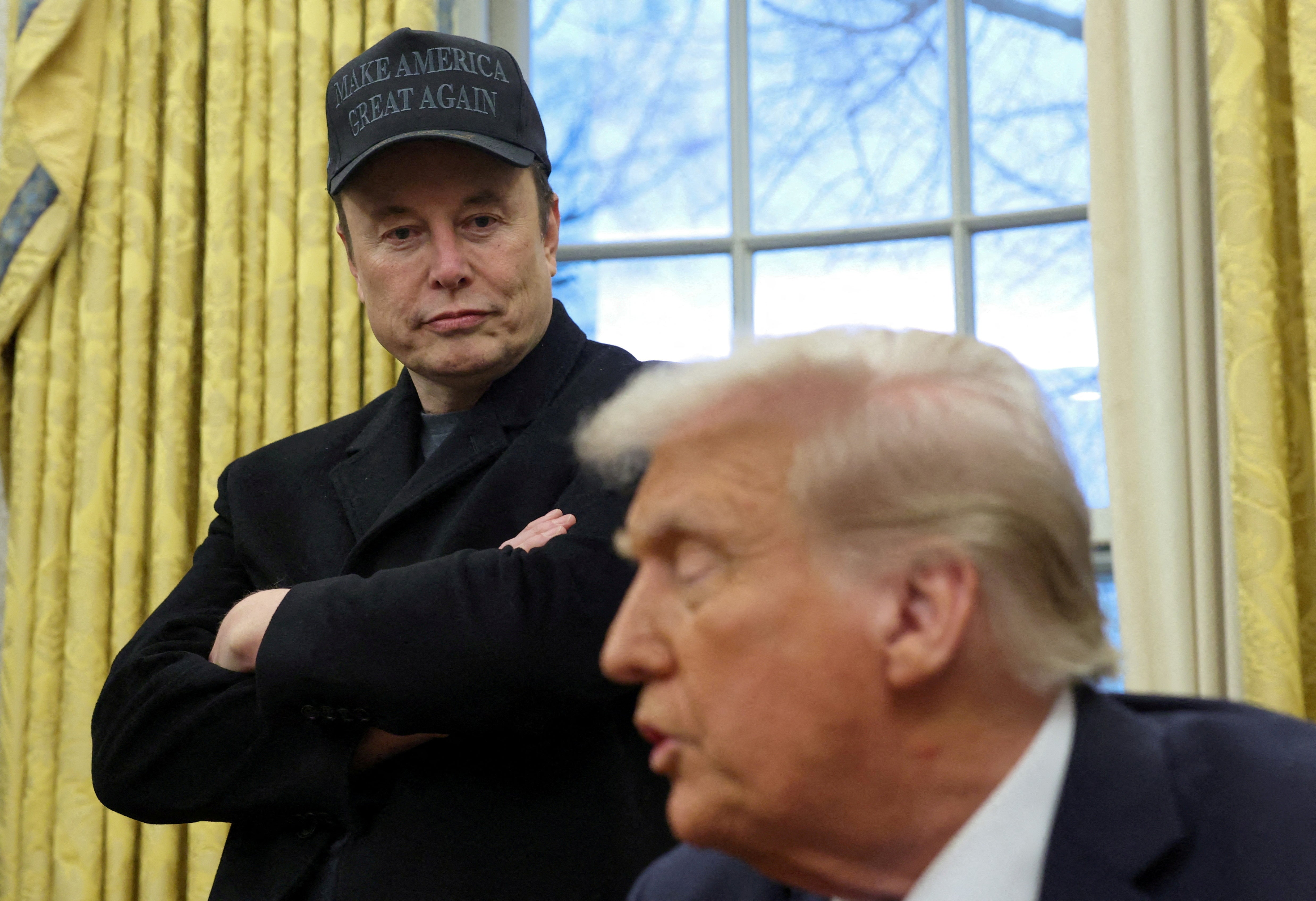 Elon Musk listens to U.S. President Donald Trump speak in the Oval Office of the White House in Washington, D.C., U.S., February 11, 2025